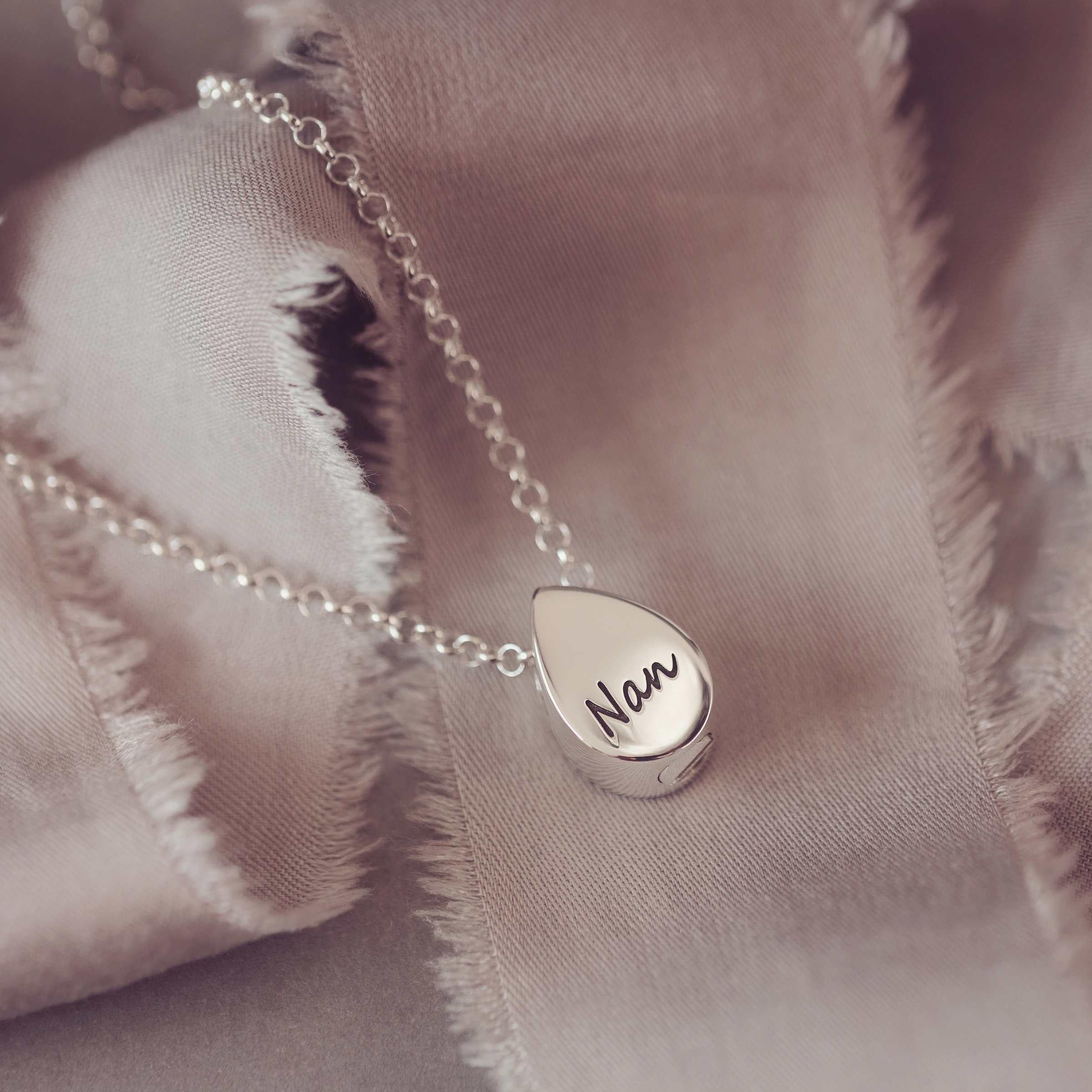 Silver necklace with a teardrop-shaped pendant engraved Nan on a soft fabric background
