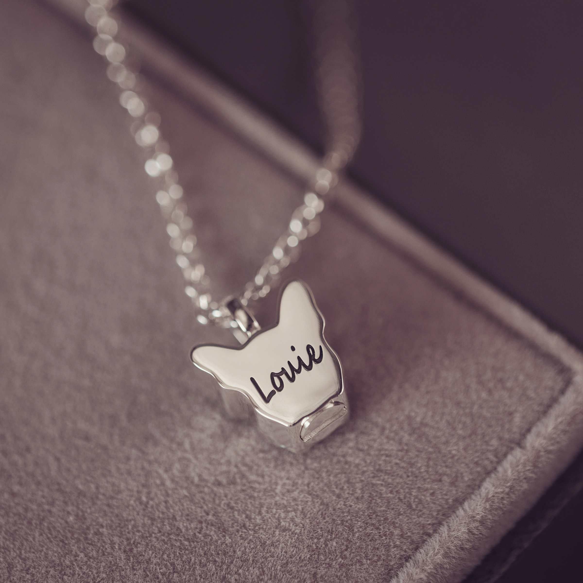 Silver necklace with Louie engraved on a textured surface
