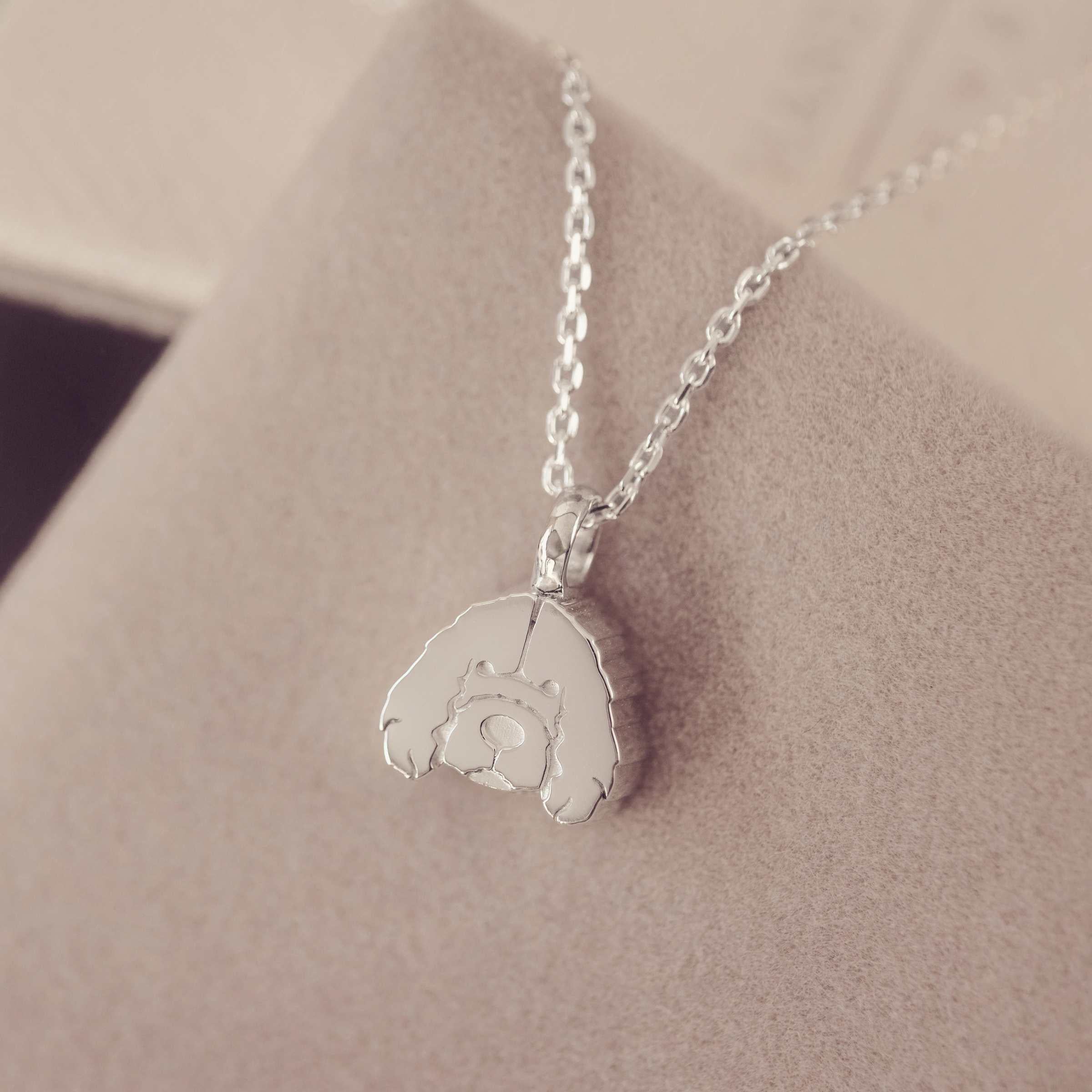 Silver necklace with a cockerpoo pendant on a soft beige background
