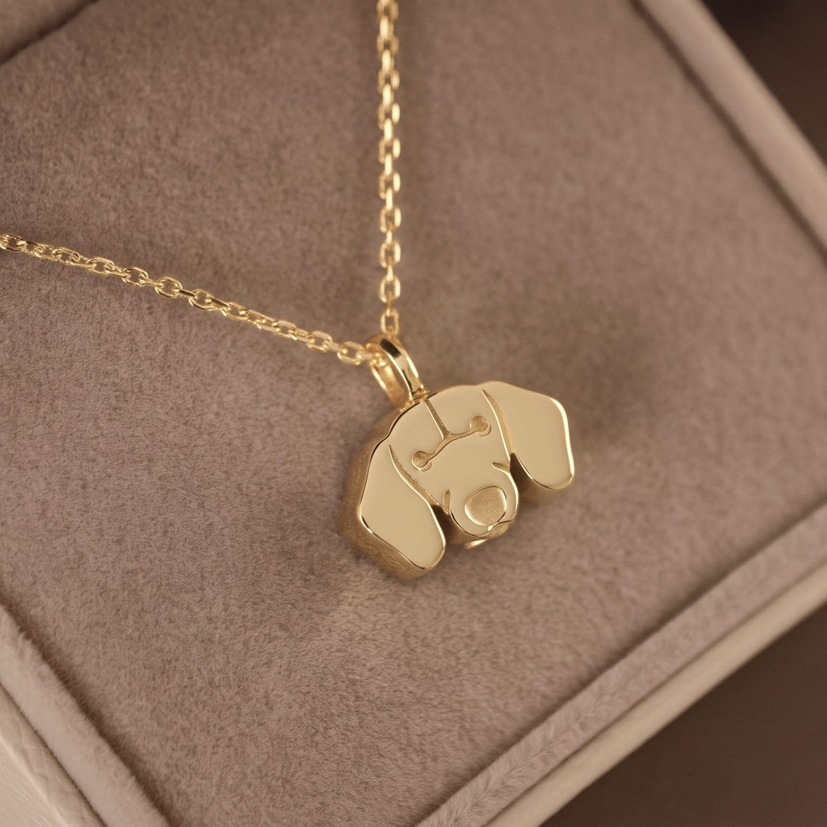 A gold necklace with a Dachshund Locket-shaped pendant resting on a textured brown jewelry box.