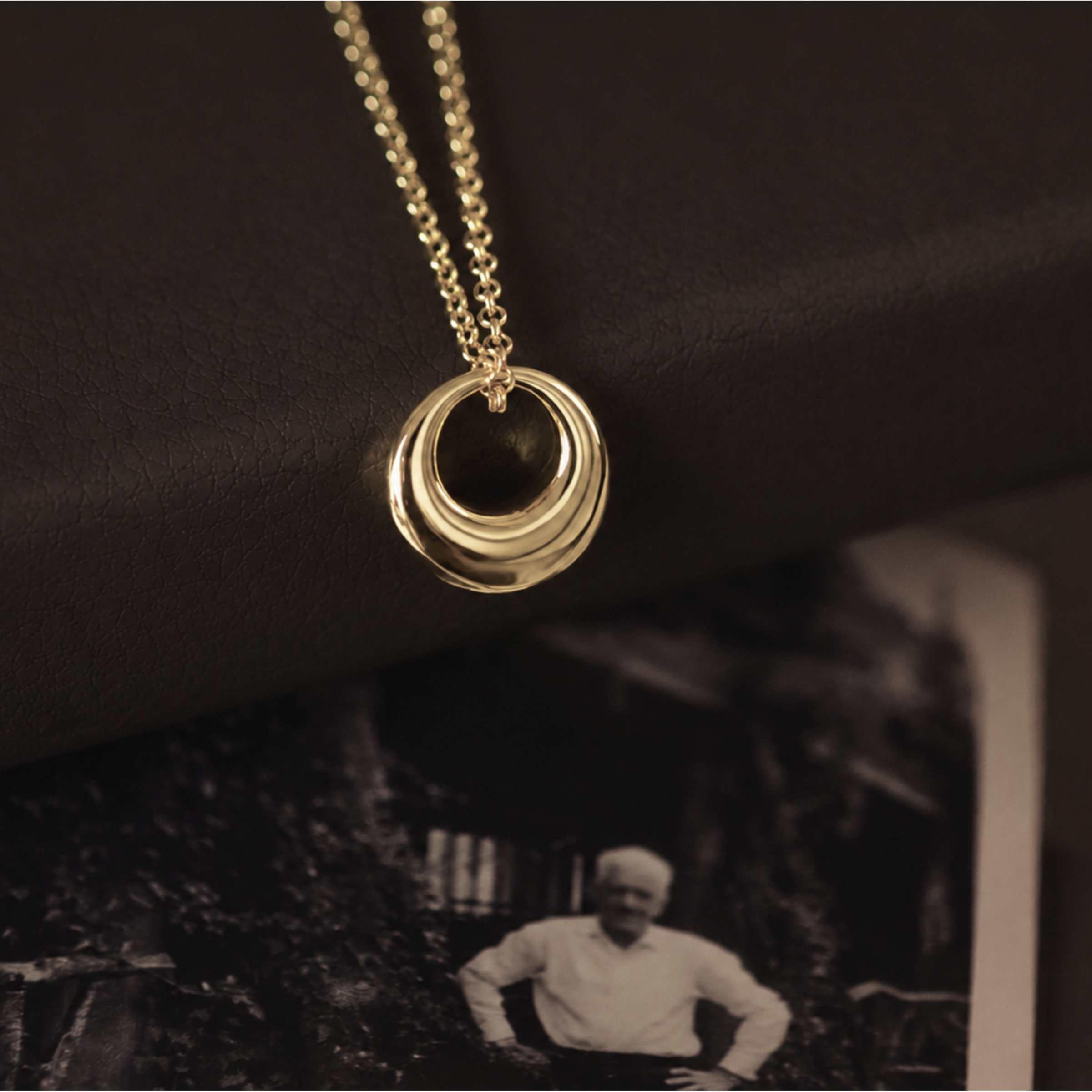 Gold necklace with a black pendant on a dark background