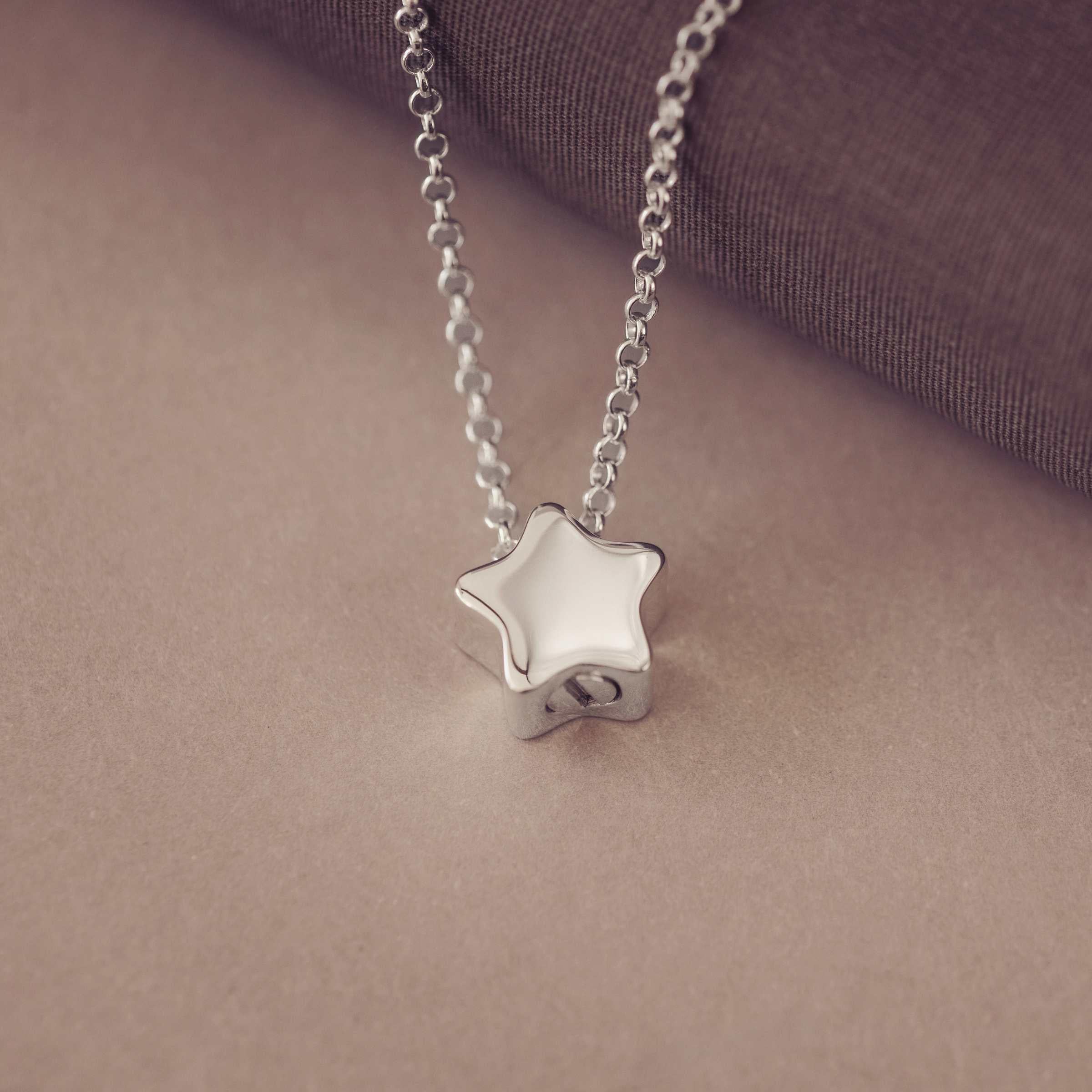 Silver star-shaped pendant on a chain against a brown background