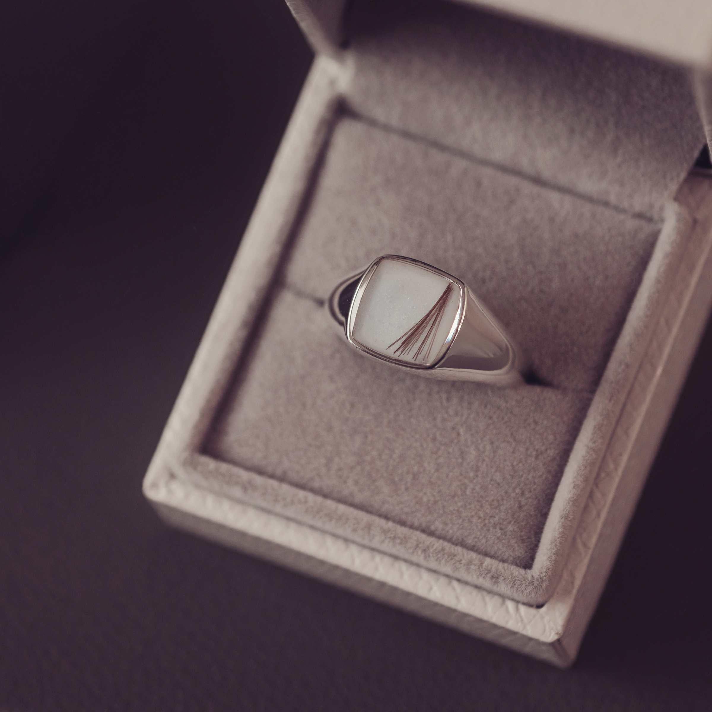 Silver ring with hair and resin in a jewelry box on a dark background