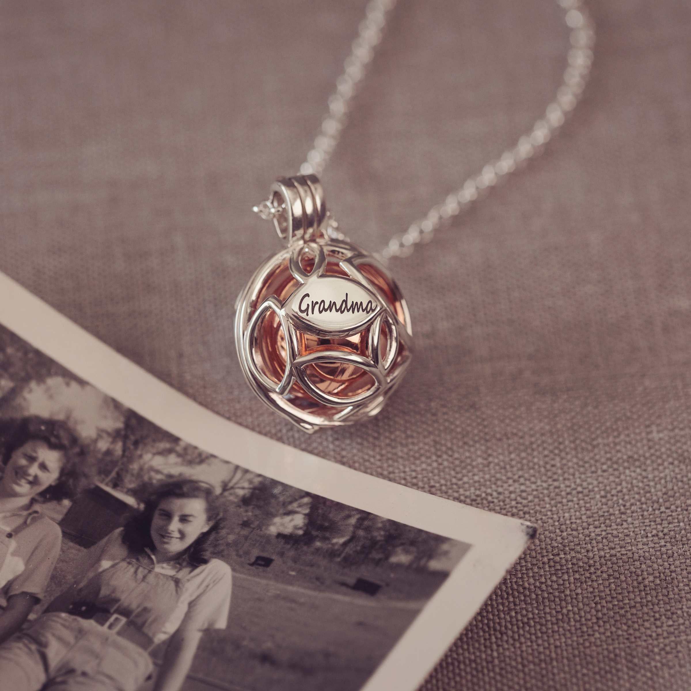 Necklace with a 'Grandma' pendant on a textured surface with an old photo underneath.