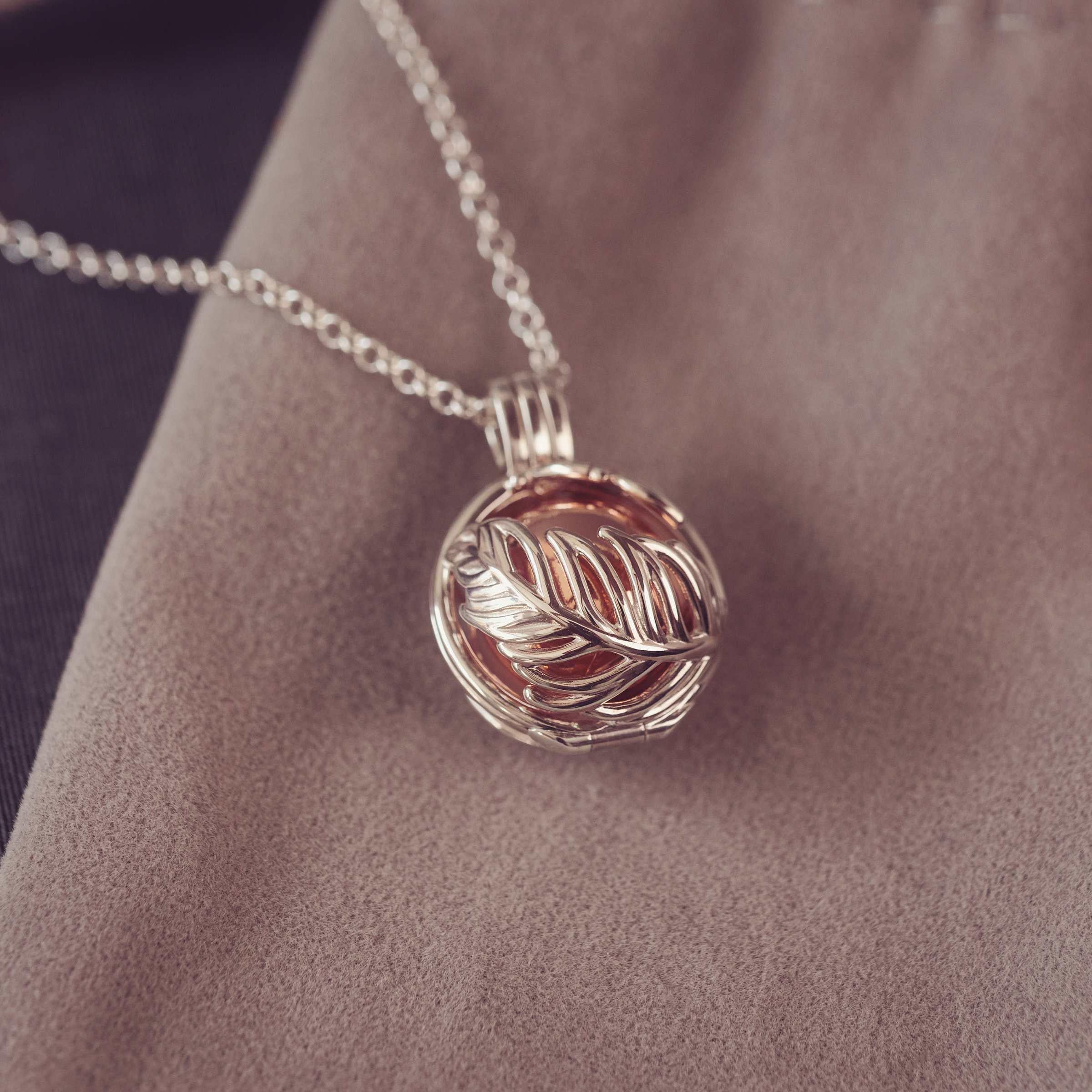 Silver necklace with a leaf-shaped pendant on fabric