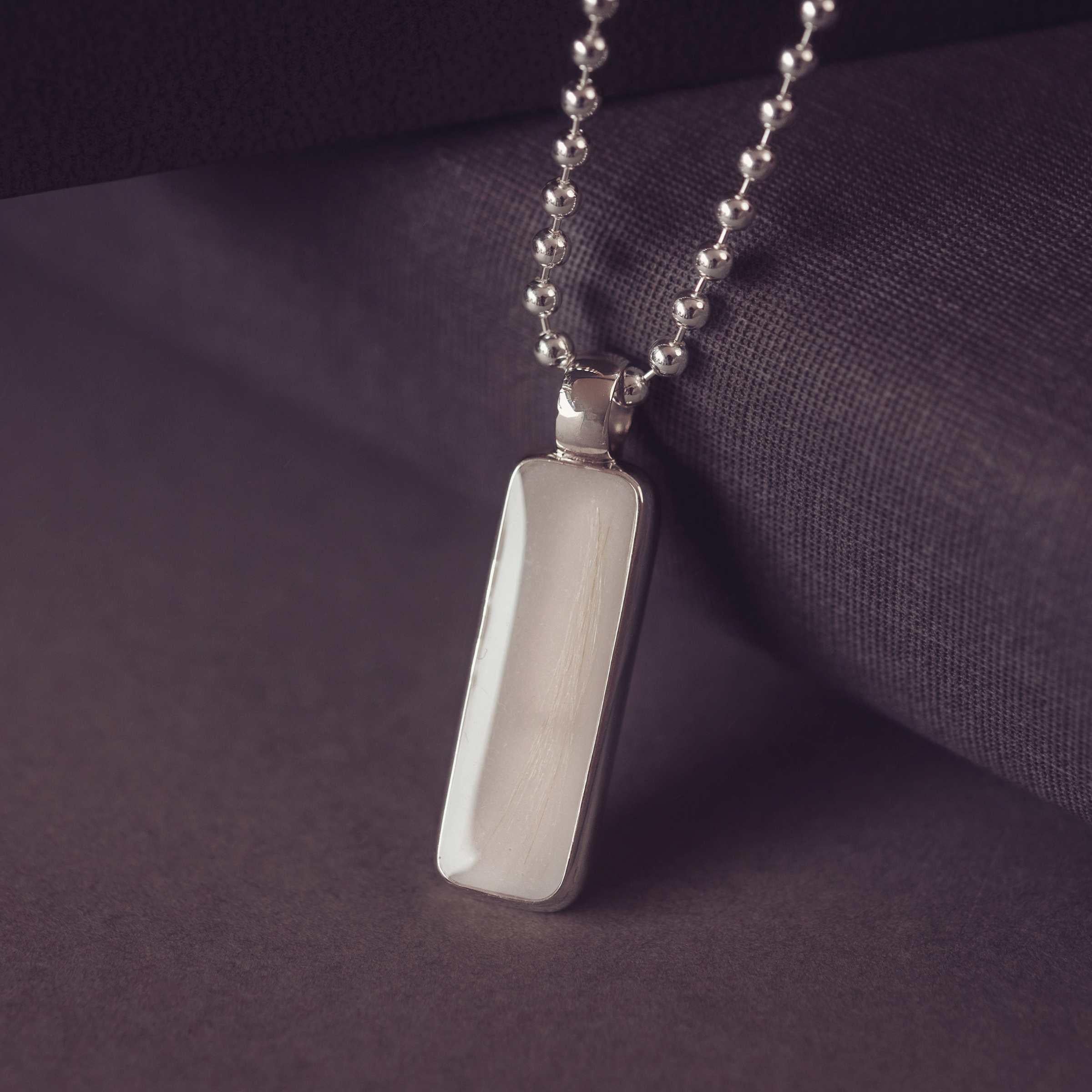 Silver pendant necklace on a dark purple fabric background