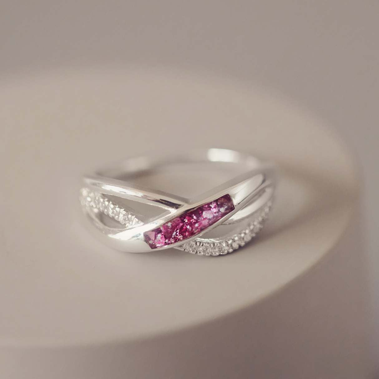 Silver ring with pink gemstone on a neutral background