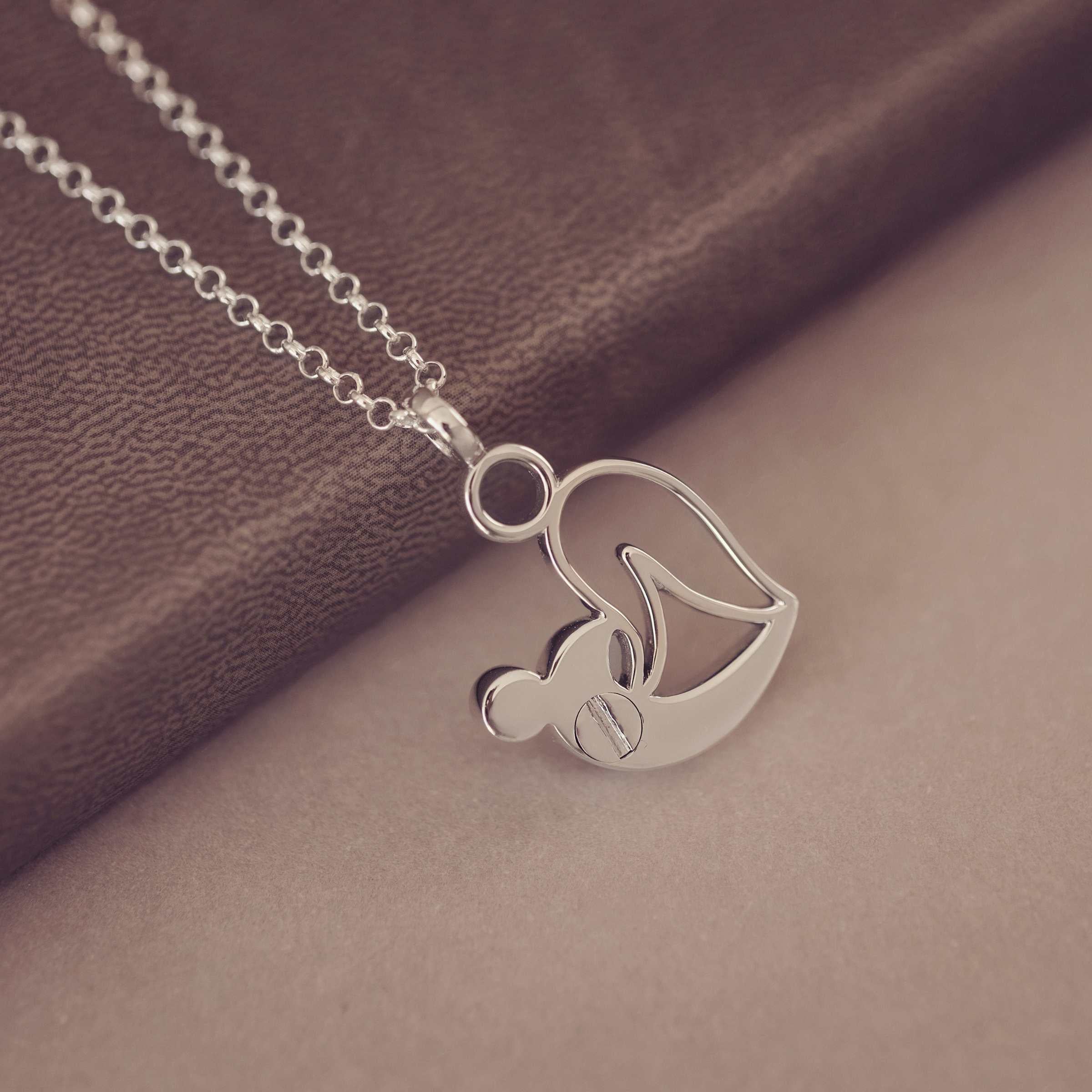 Showing the back of a Silver Urn necklace on a brown fabric background