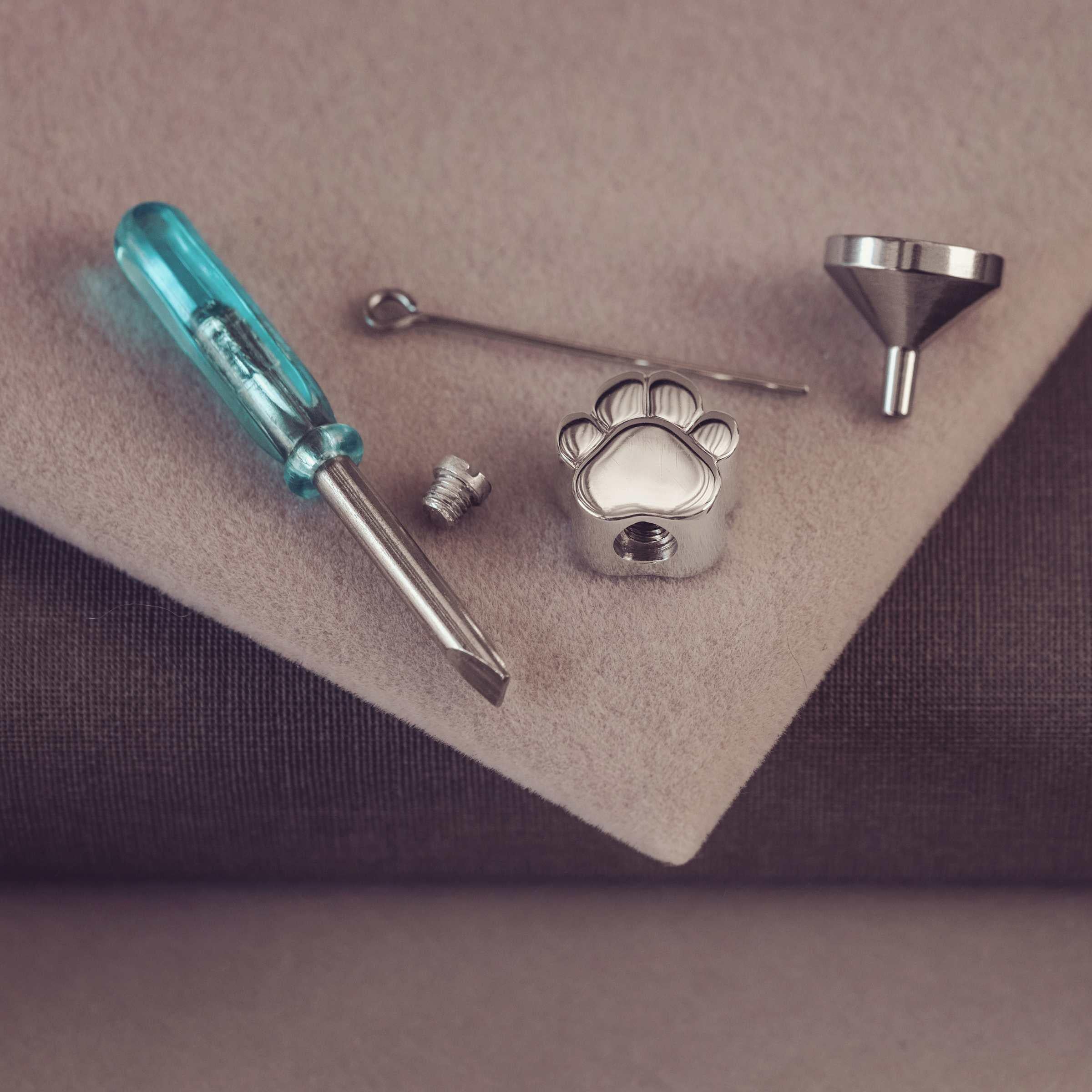 Metallic paw-shaped object with tools on a brown surface