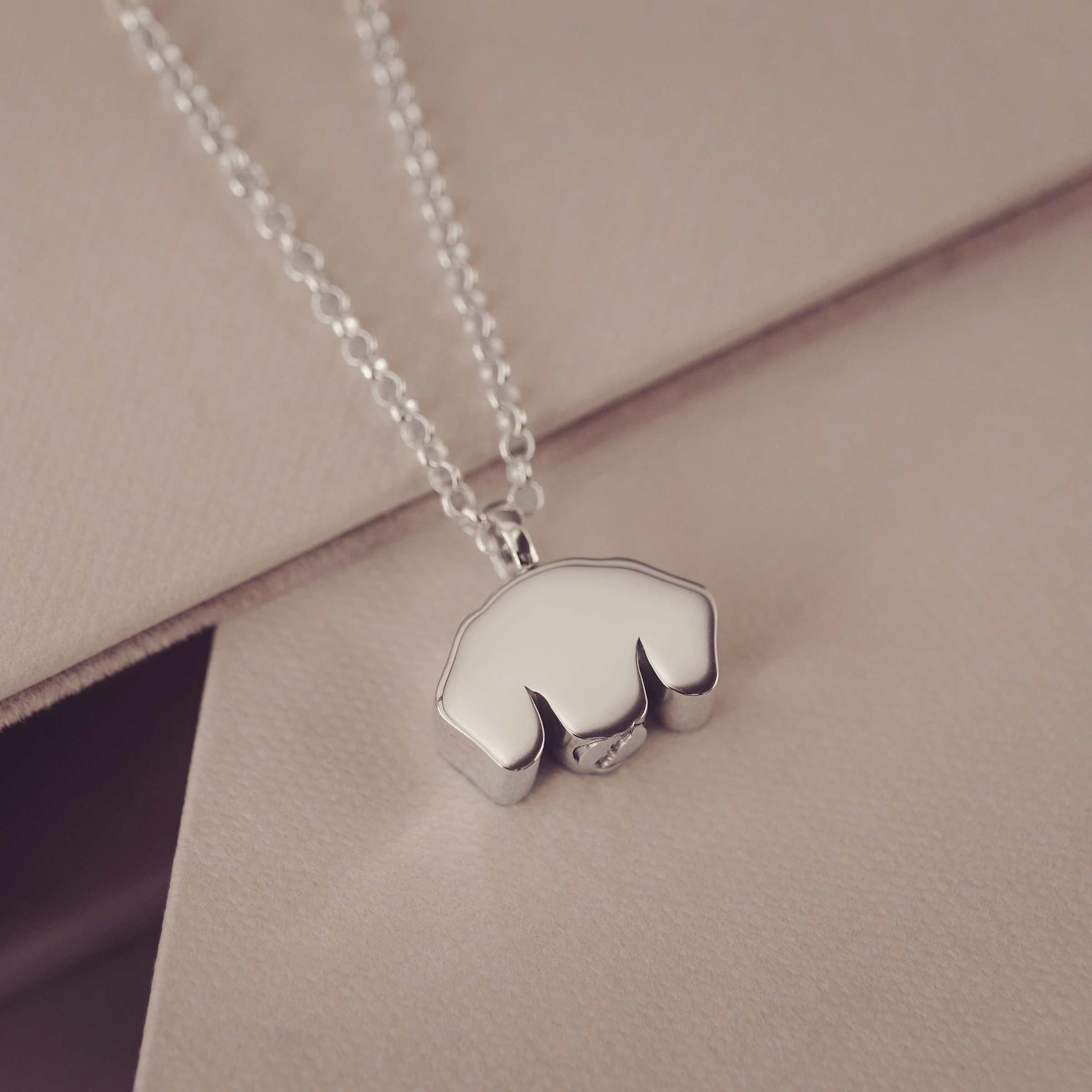 Silver necklace with a back of dog-shaped pendant on a beige surface