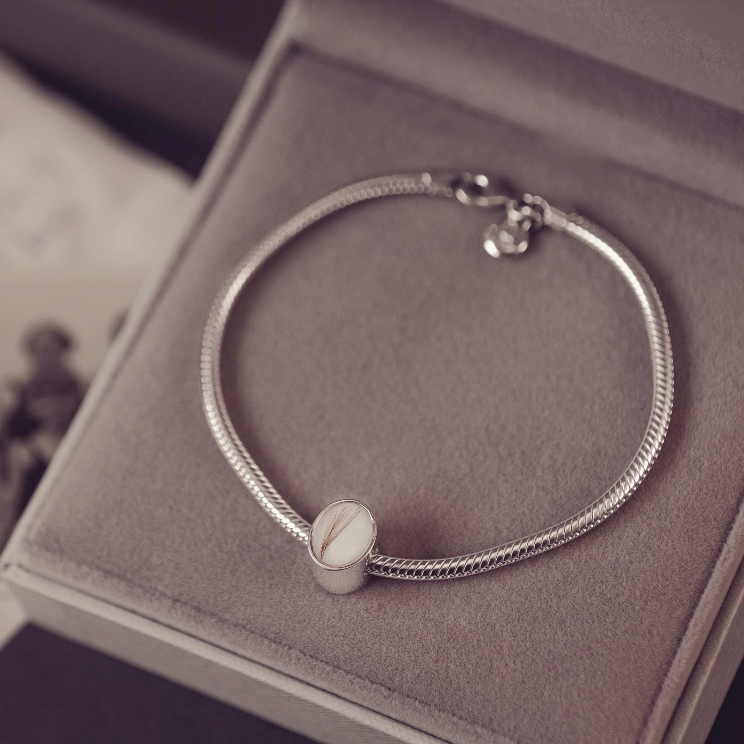 Silver bracelet with a oval charm on a soft surface