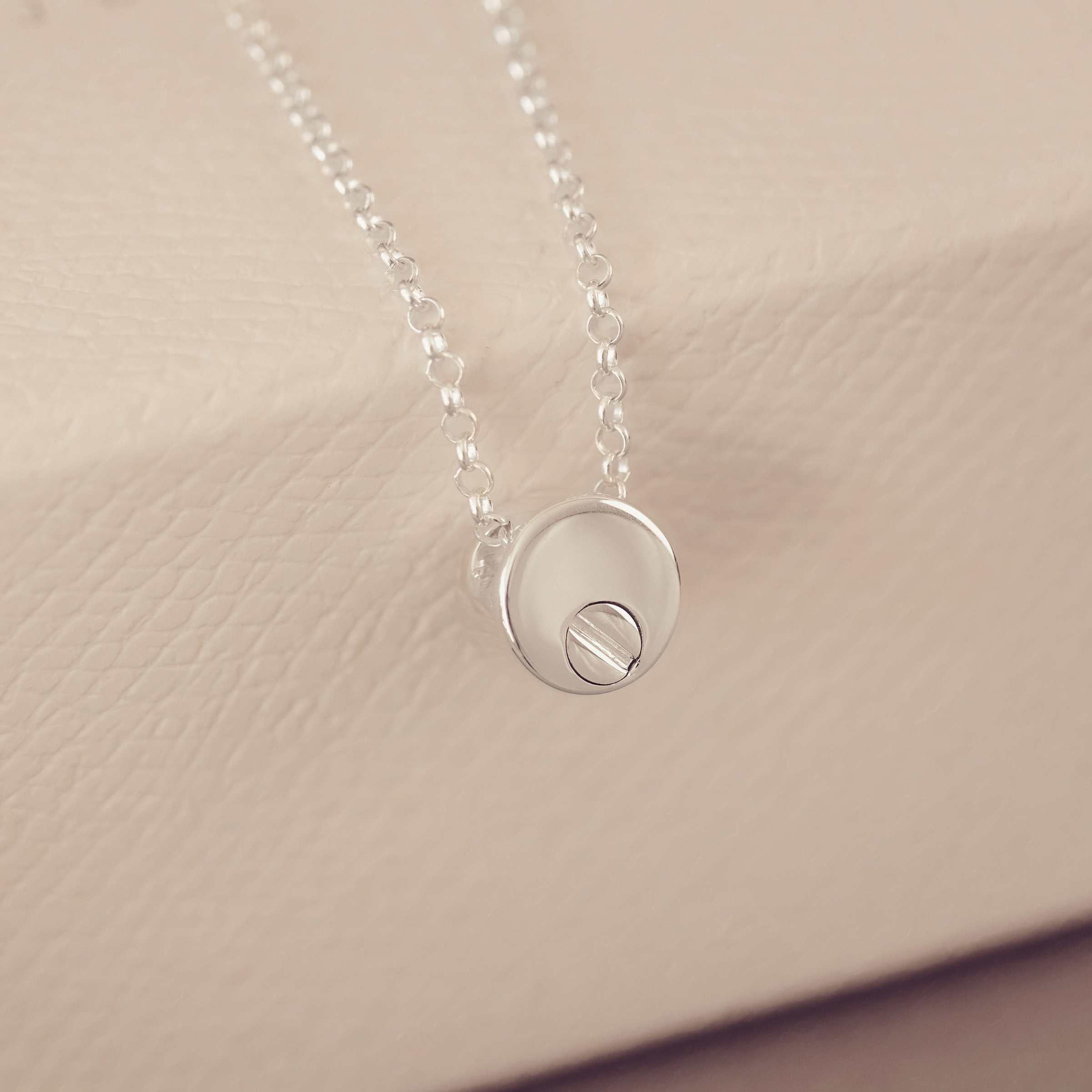 Silver necklace with a round pendant on a beige background