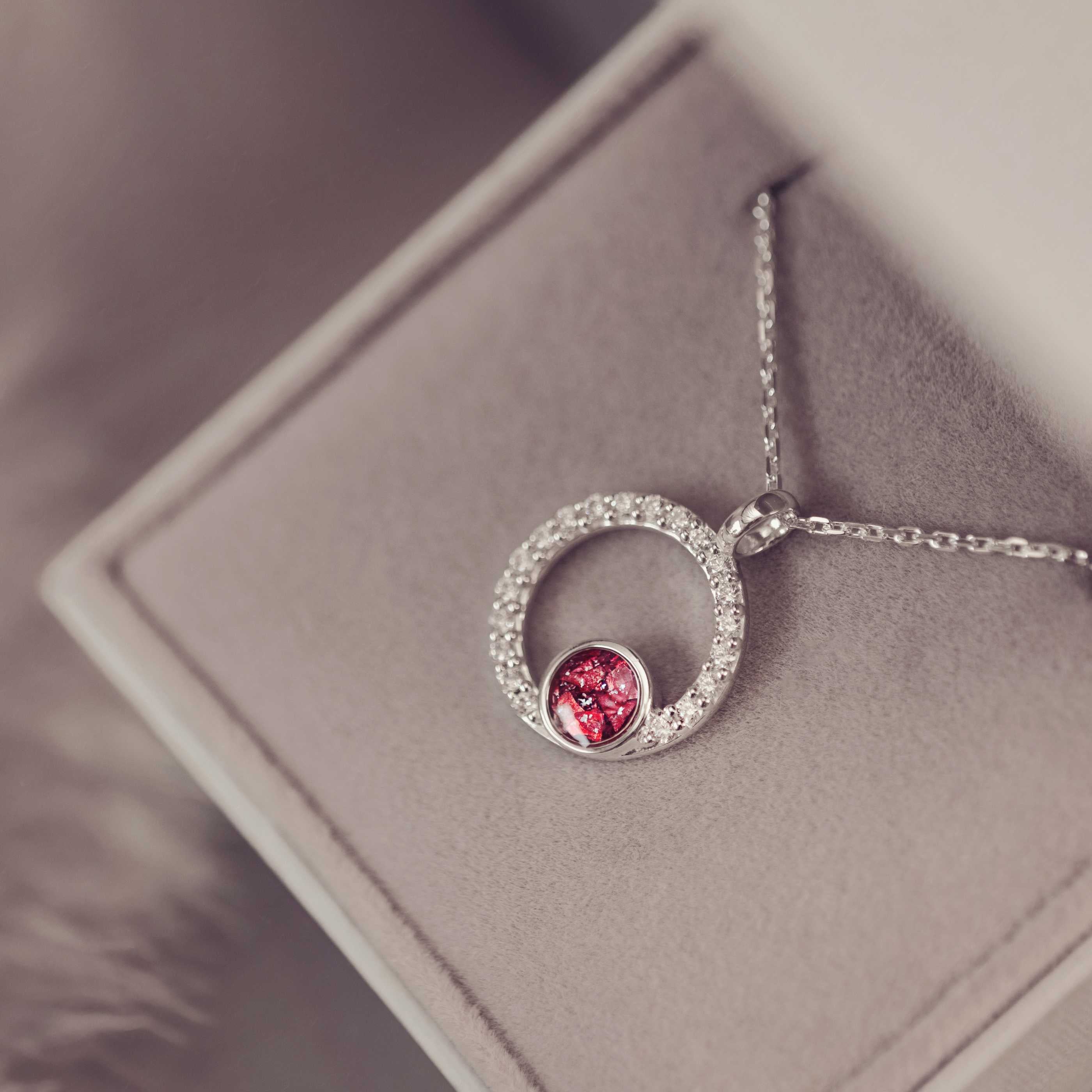 Silver necklace with a red gemstone pendant on a soft gray surface