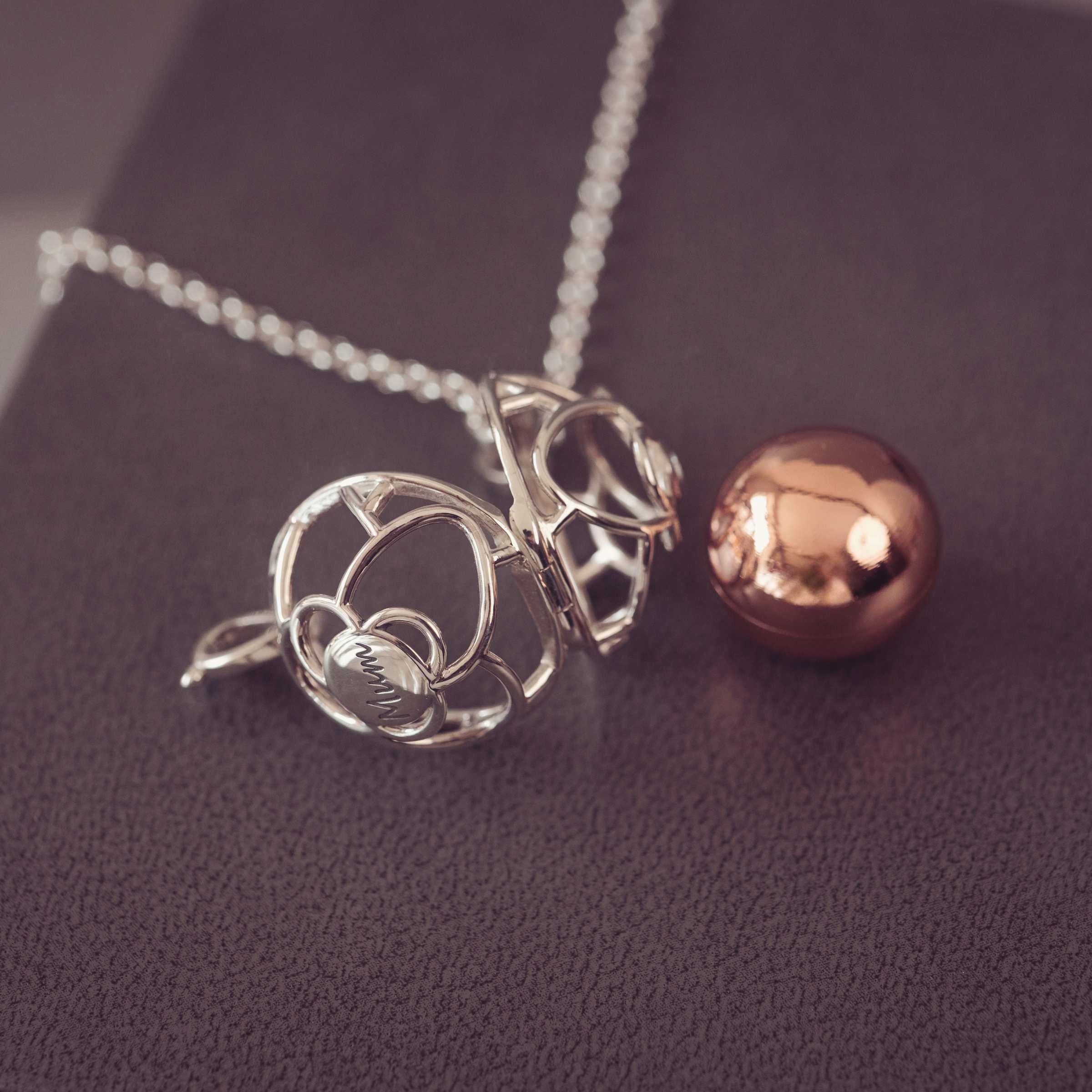 Silver pendant and rose gold sphere on a dark fabric background