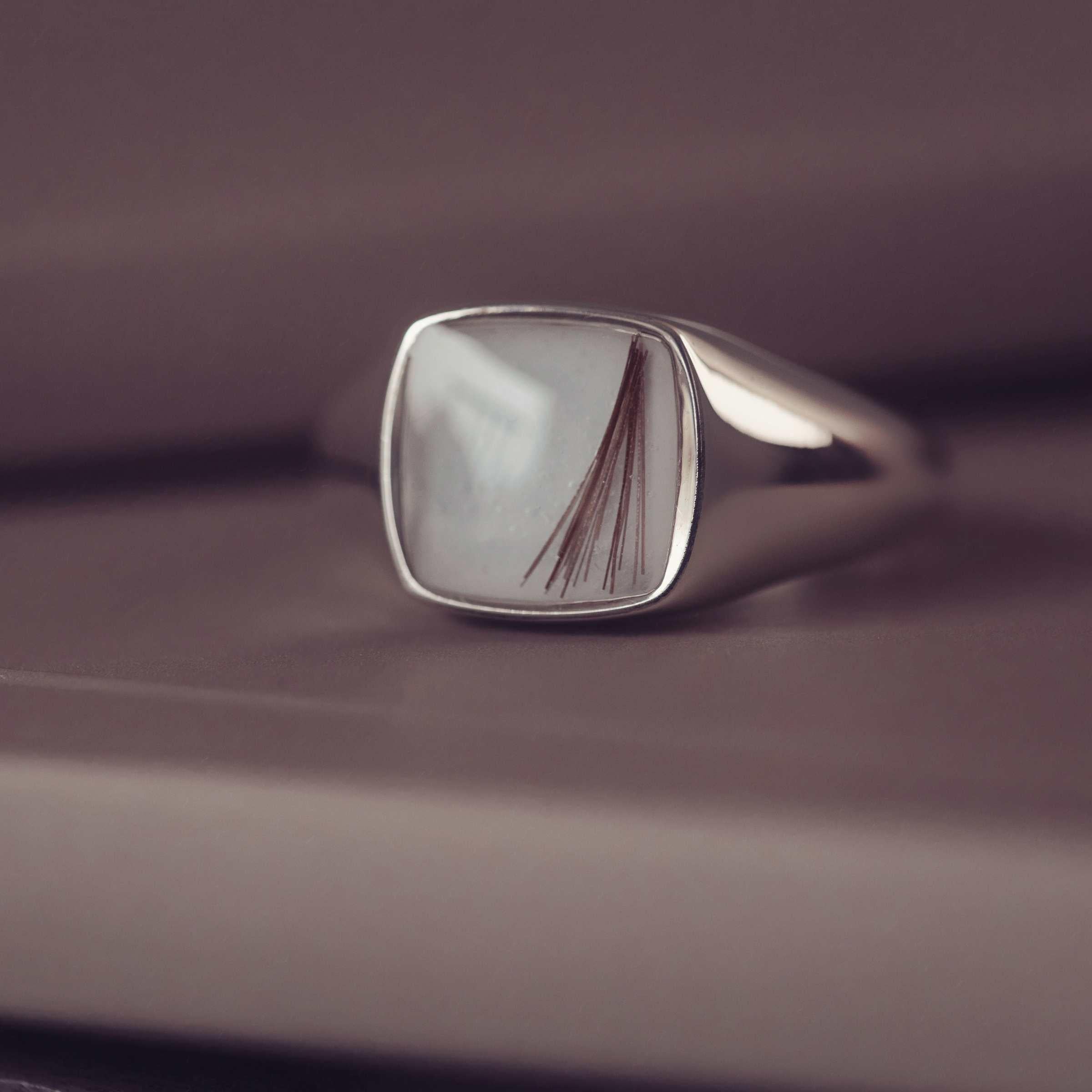 silver cushion signet ring on a dark backgrounf