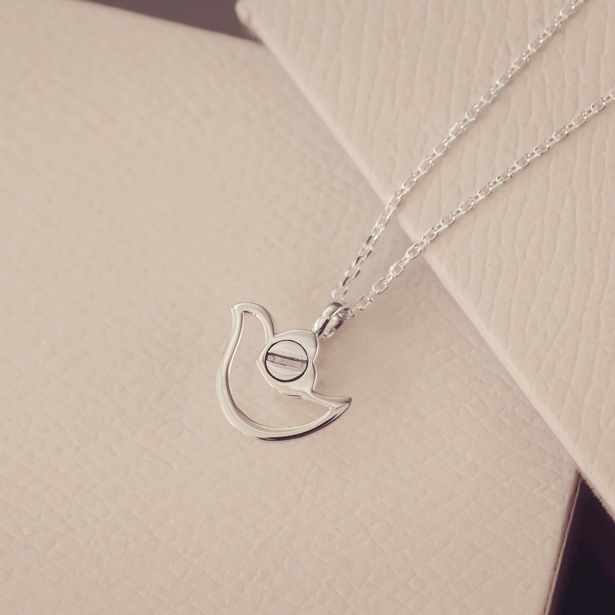 The back of a Silver urn necklace on a beige surface