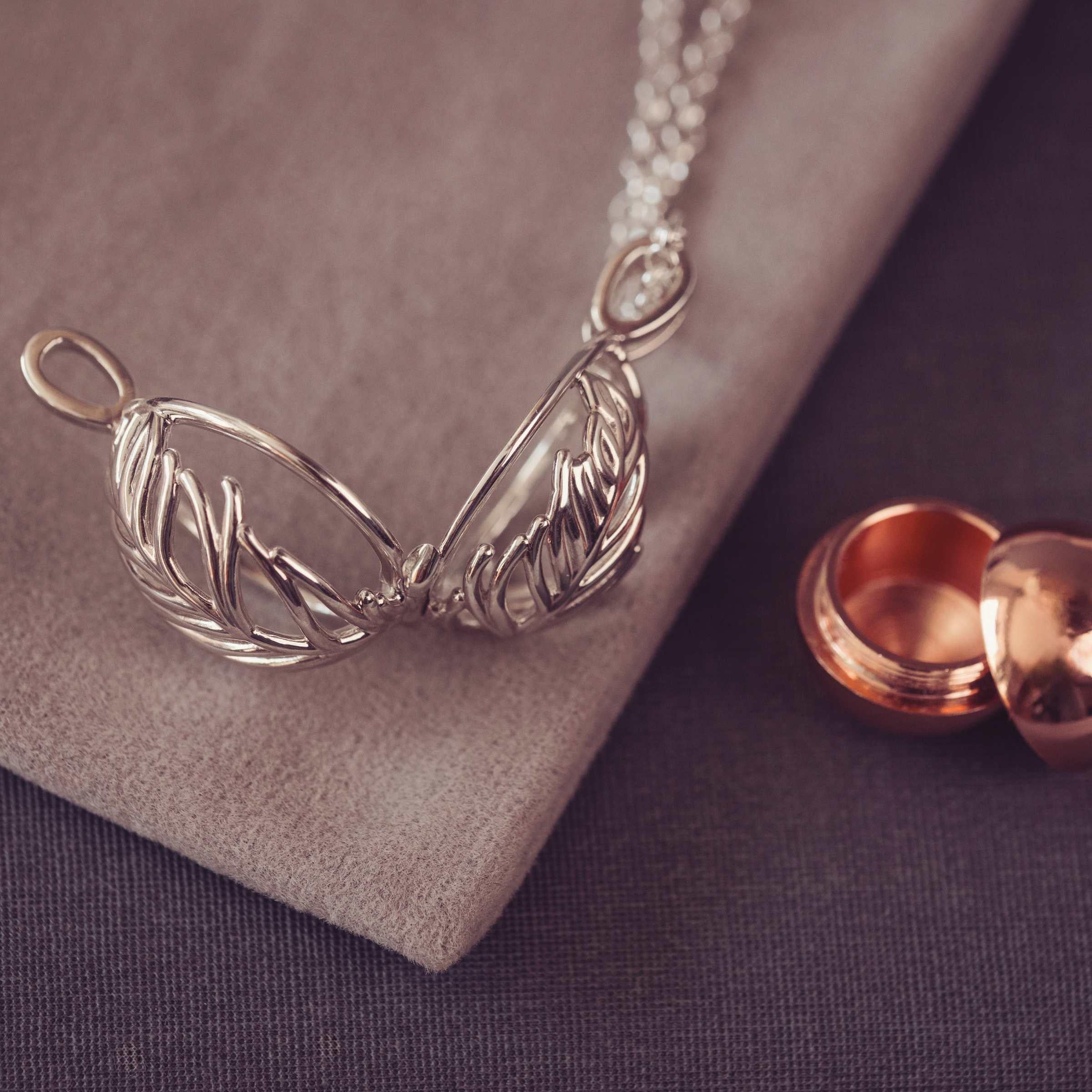 Silver necklace with feather-like pendants on a textured surface