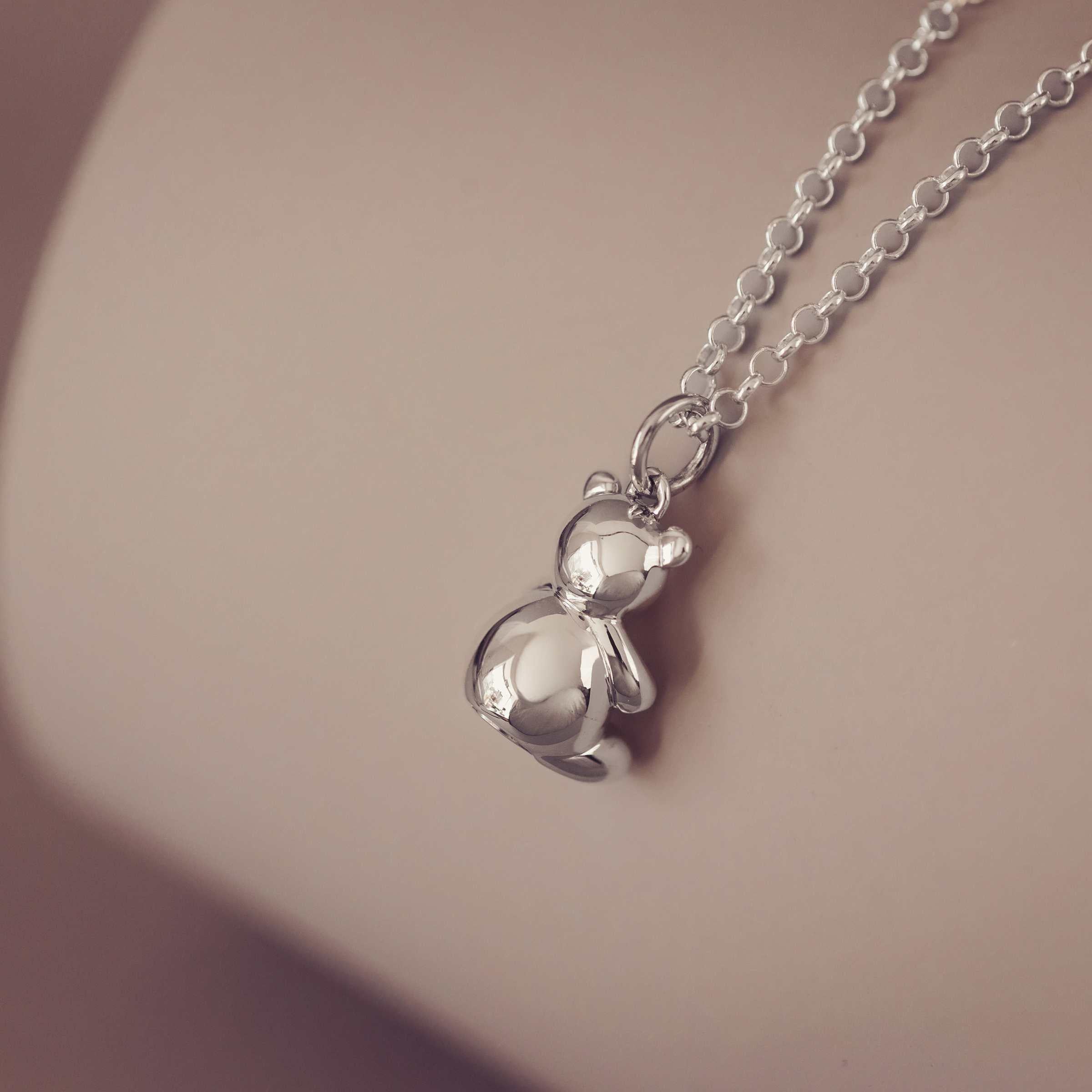 Silver Teddy bear pendant on a chain against a soft background