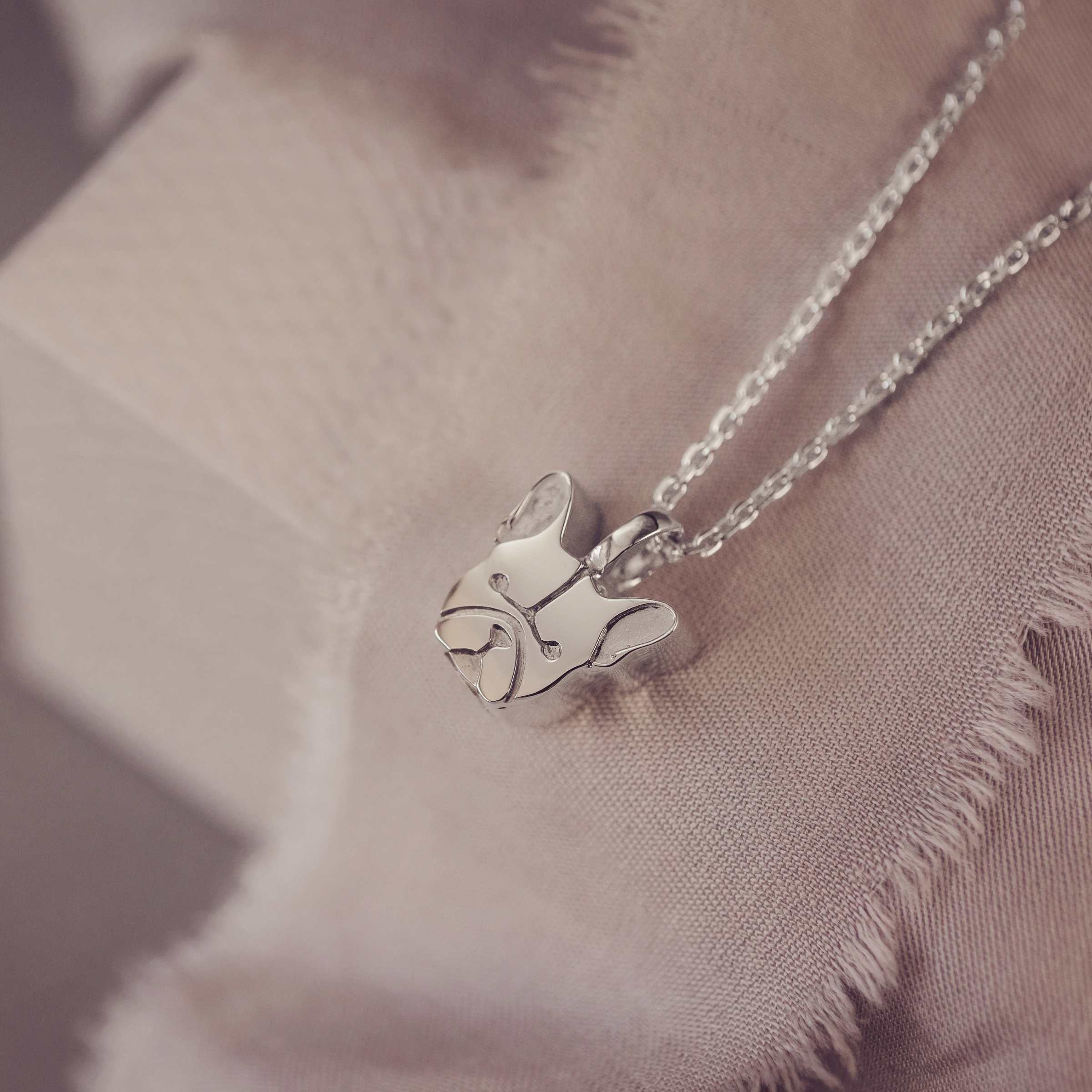 Silver French bull dog pendant necklace on a soft fabric background