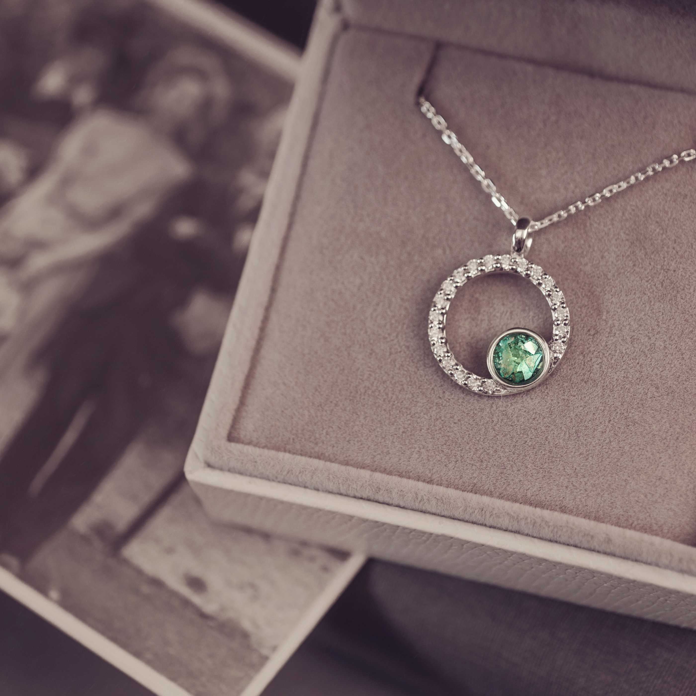 Silver necklace with a green gemstone pendant on a textured surface