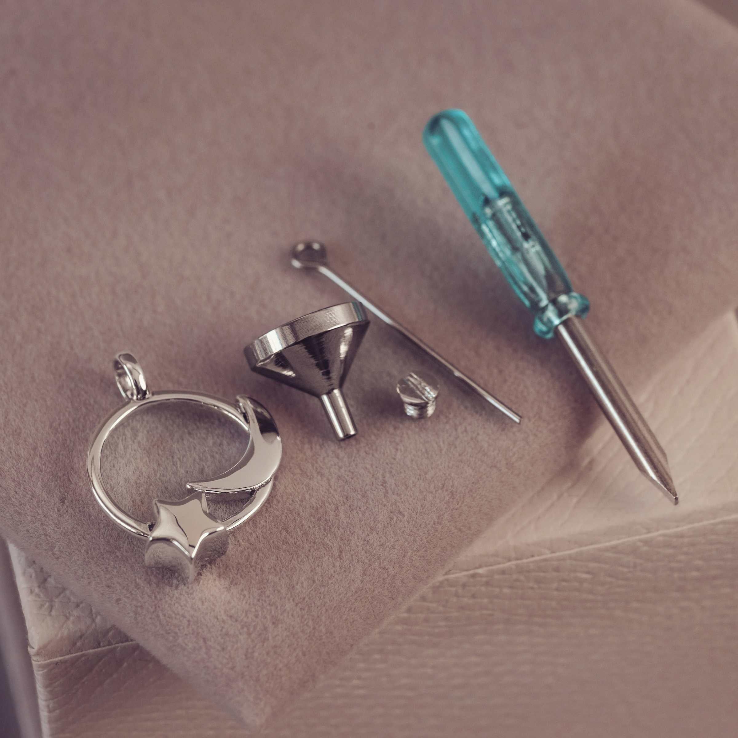 Metal jewelry components and a screwdriver on a textured surface