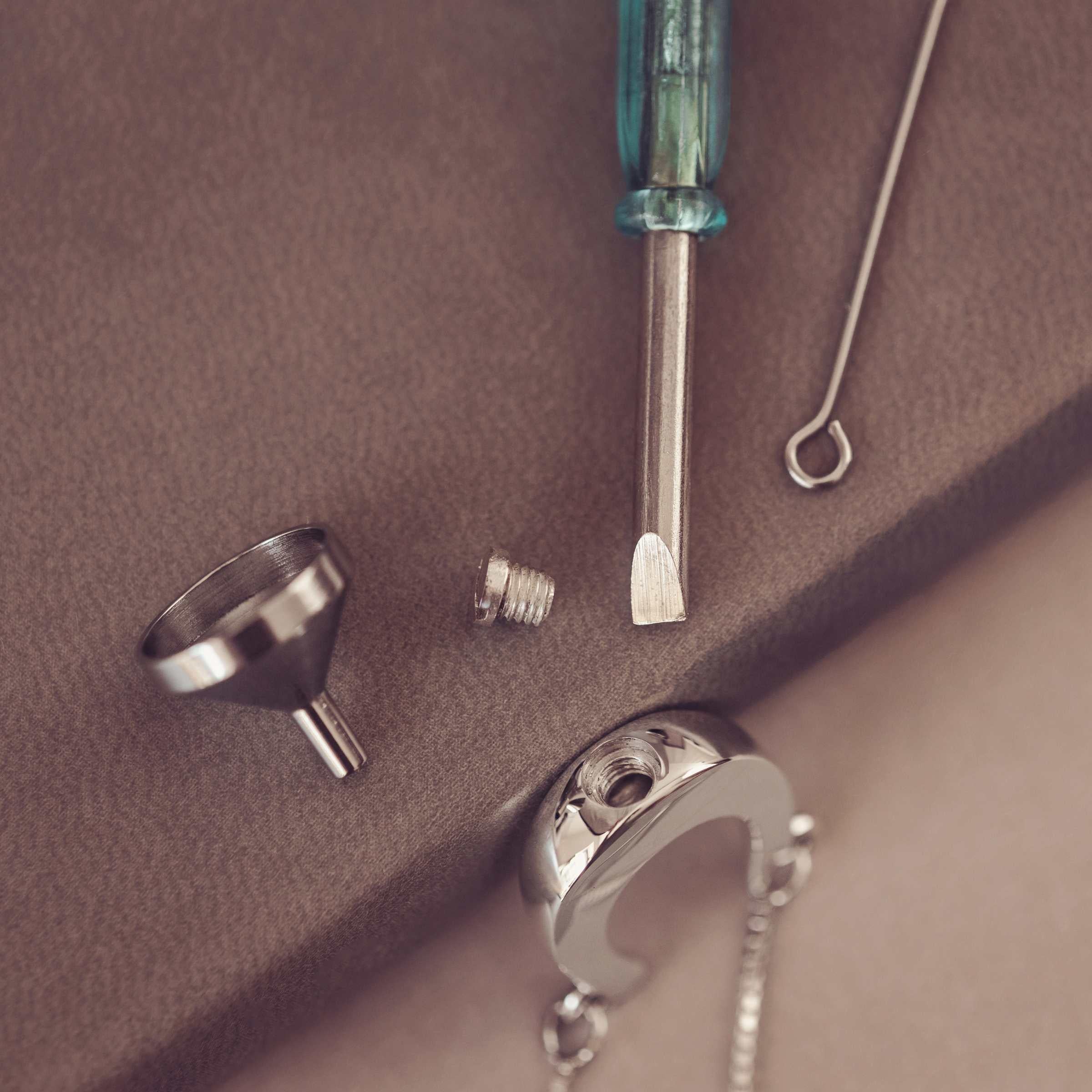 Jewelry-making tools including a funnel, screwdriver on a brown surface.