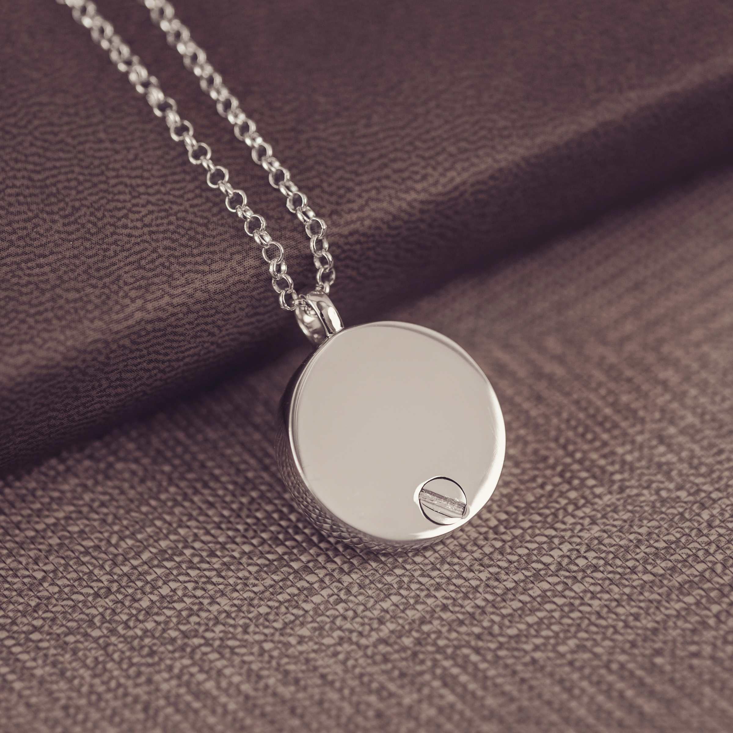 Silver pendant necklace on a textured brown fabric background