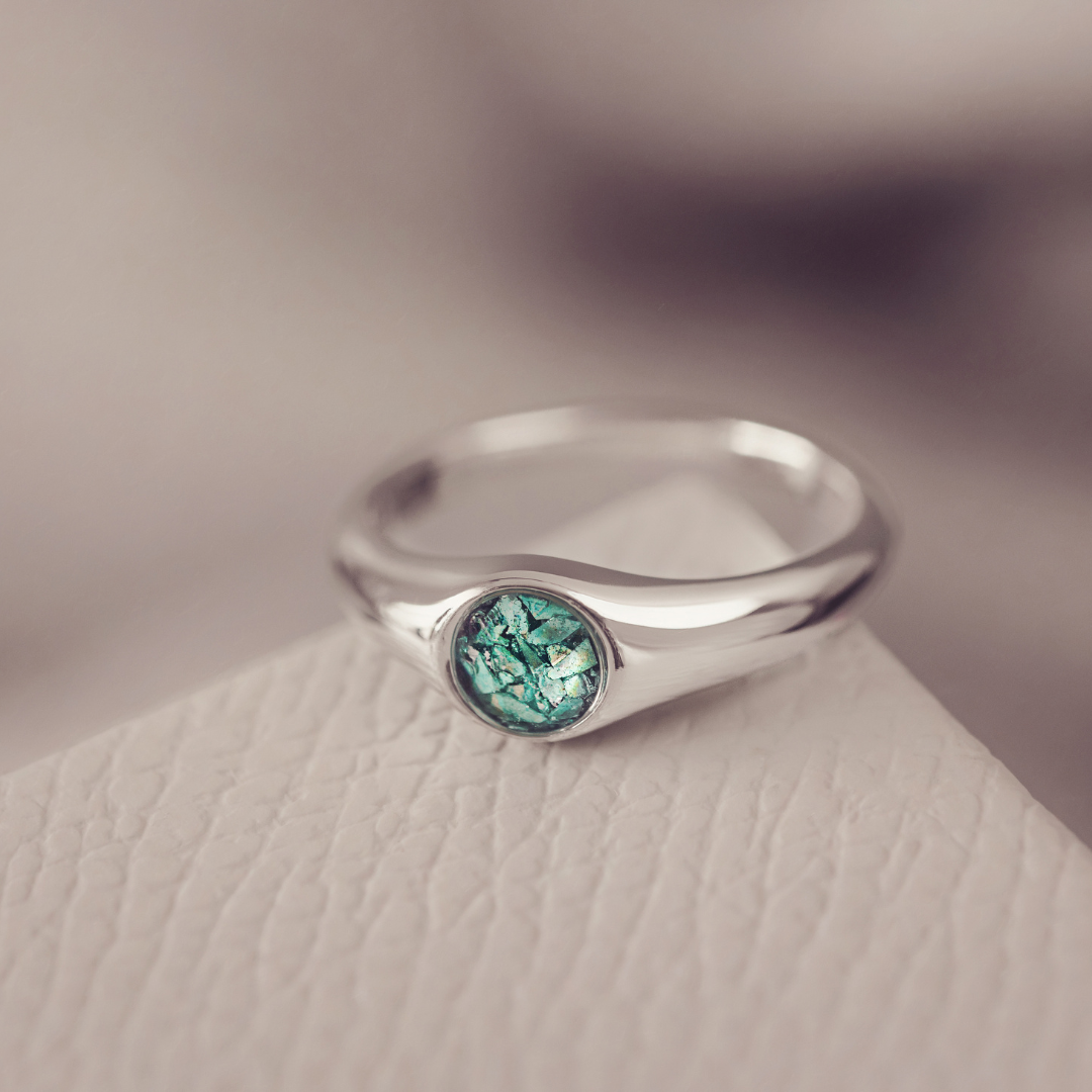 Silver ring with a green gemstone on a textured surface