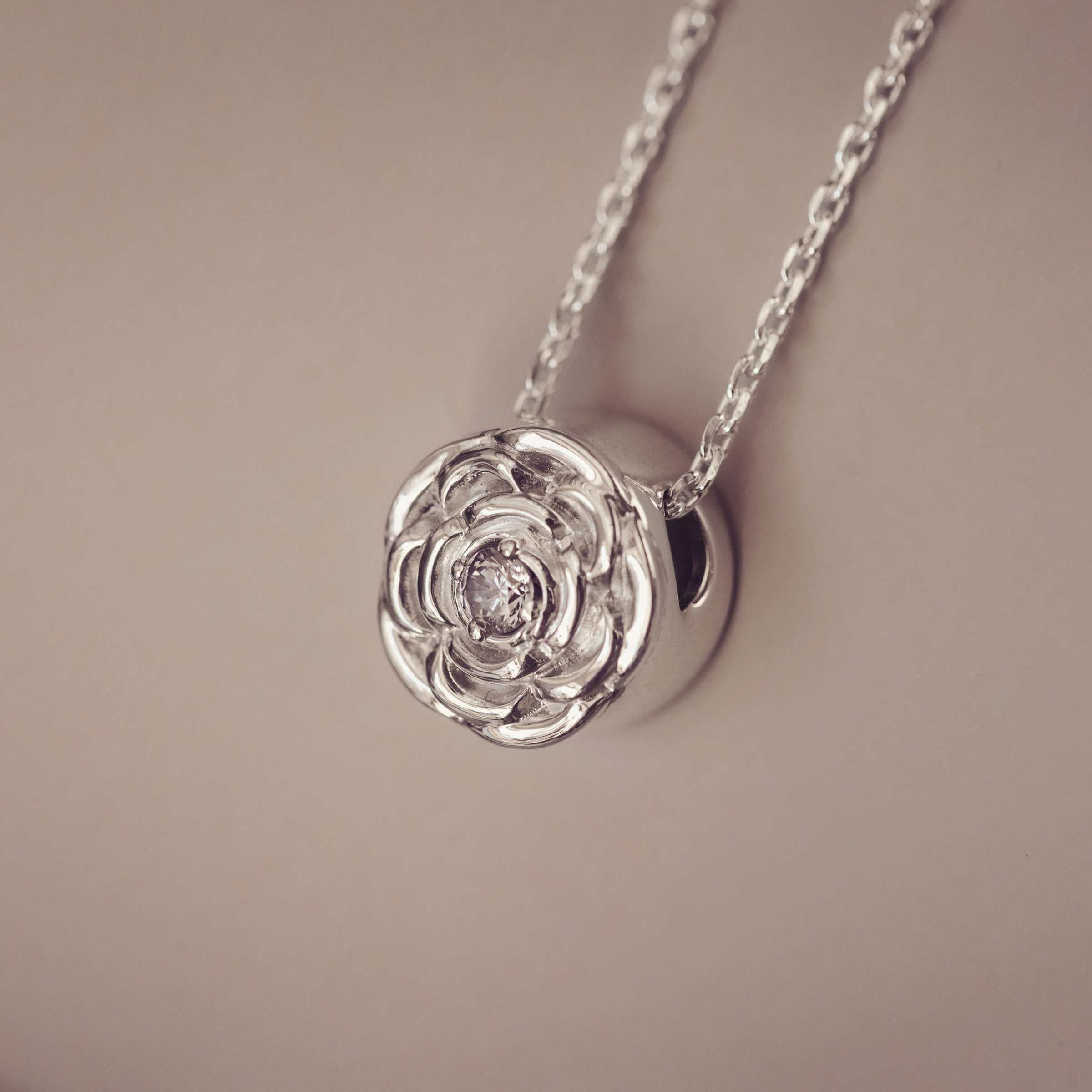 Silver rose-shaped pendant necklace on a beige background