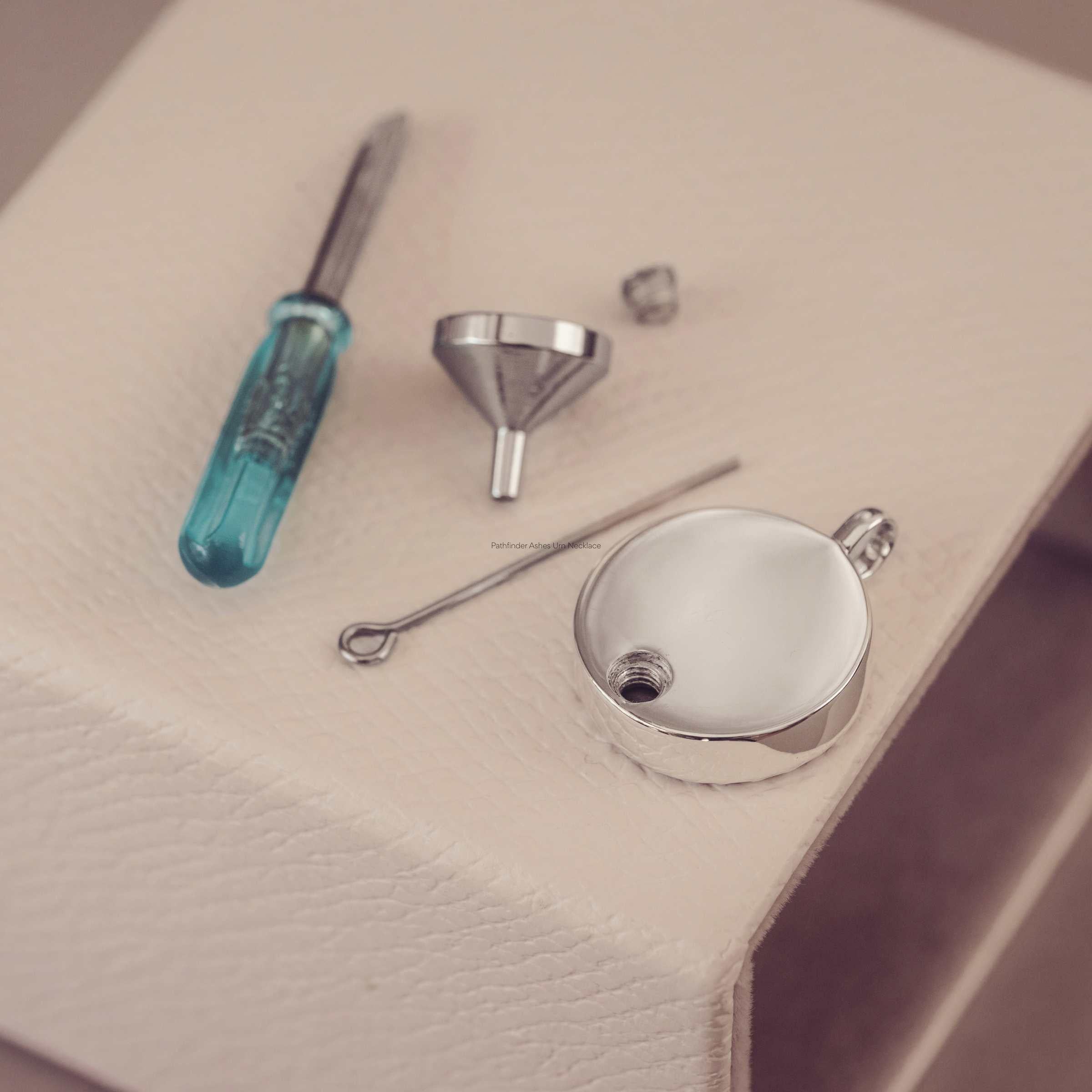 Set of tools including a screwdriver, funnel, and metal components on a beige surface.