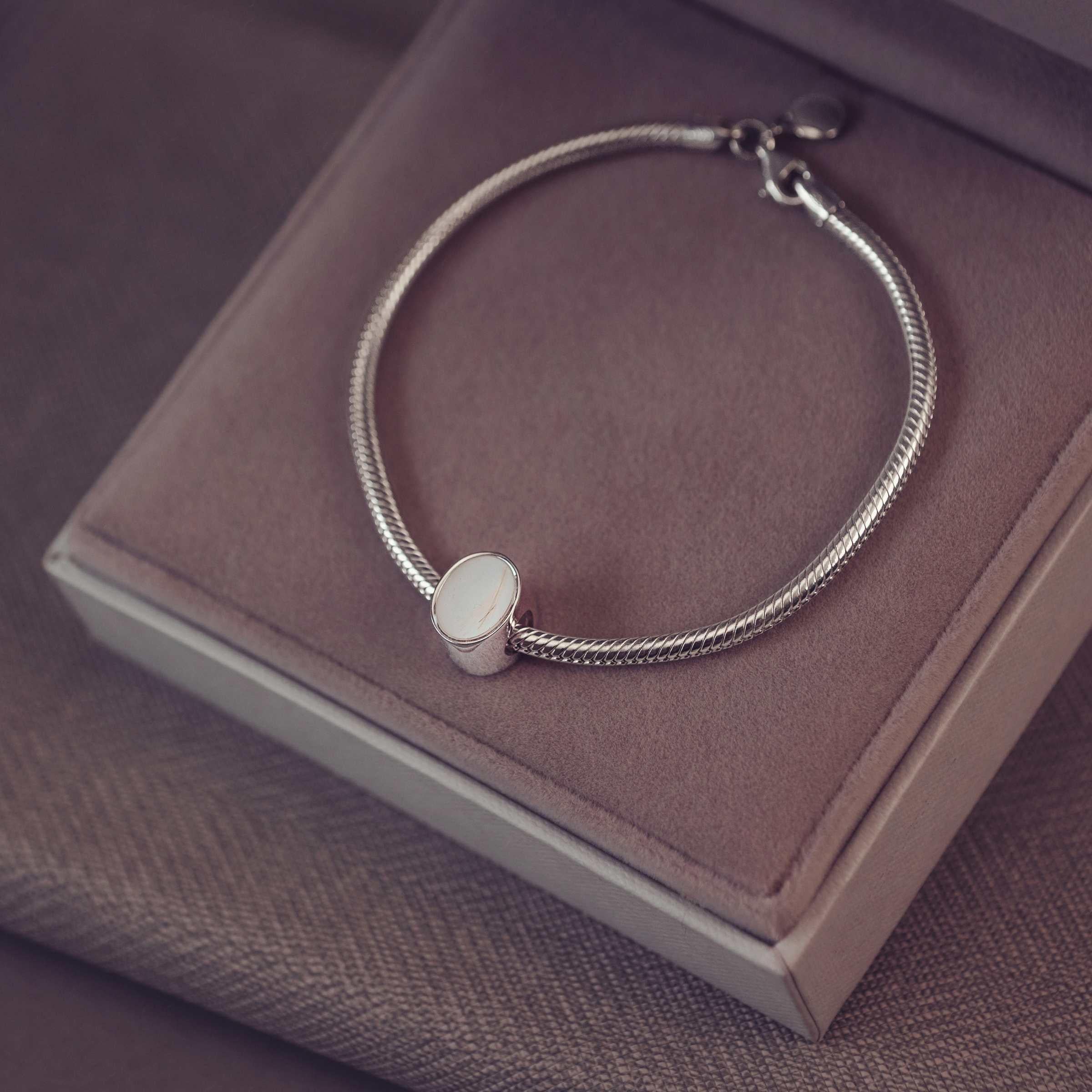 Silver bracelet with an oval charm on a jewellery box