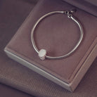 Silver bracelet with an oval charm on a jewellery box