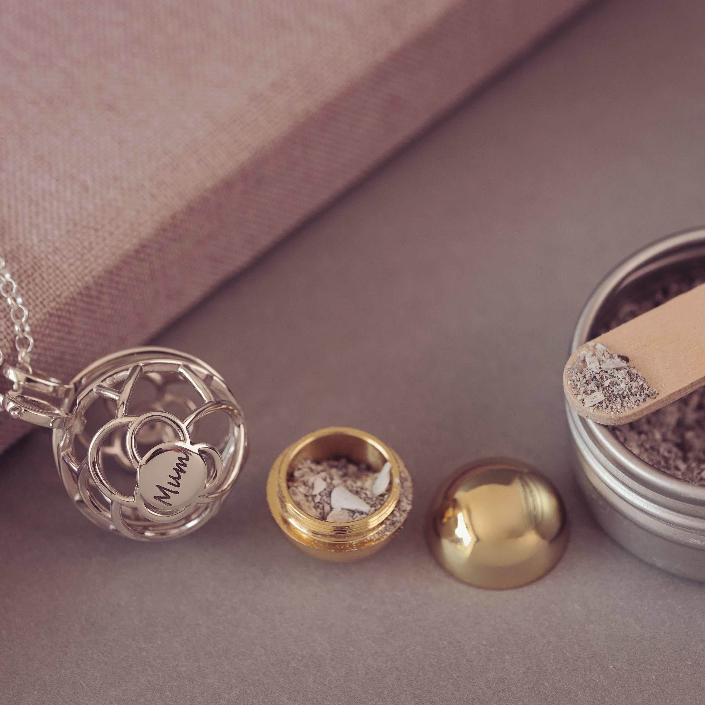 Silver necklace with a locket, gold  container of ashes on a neutral background