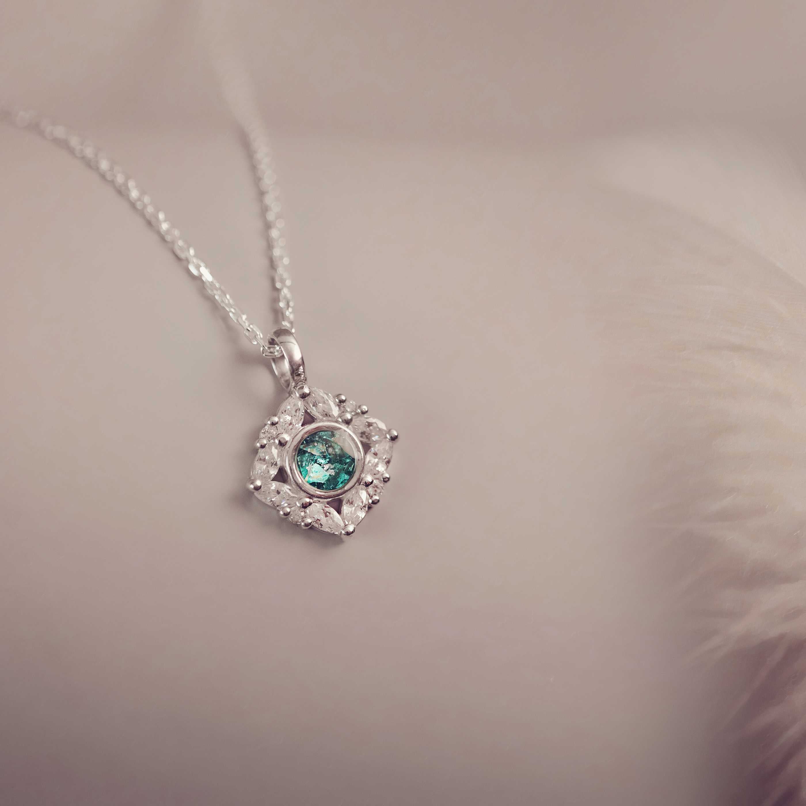 Silver heart-shaped pendant with a green gemstone on a soft background