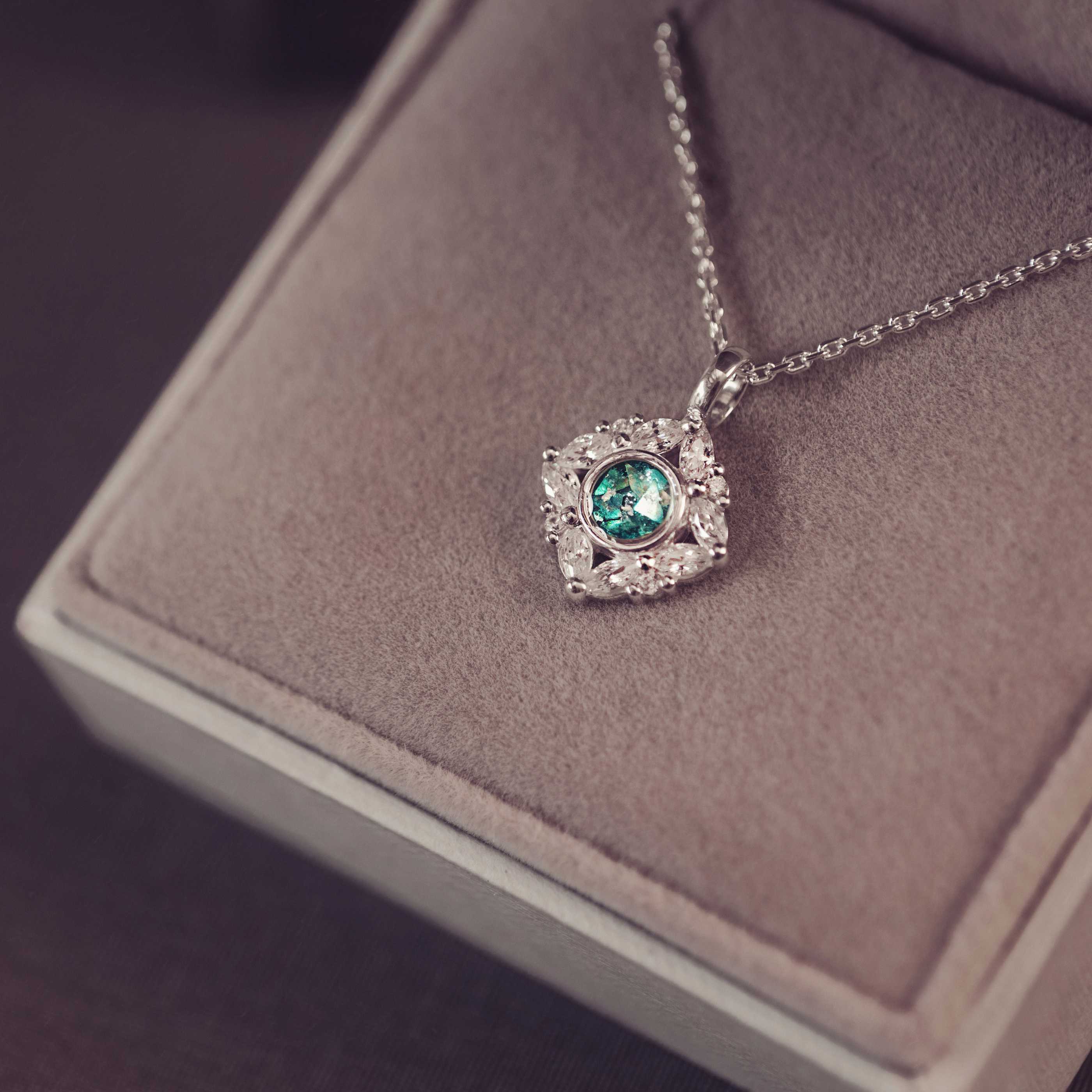 Silver necklace with a green gemstone pendant on a soft surface