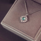 Silver necklace with a green gemstone pendant on a soft surface