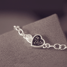 Silver bracelet with a heart-shaped charm on a textured surface