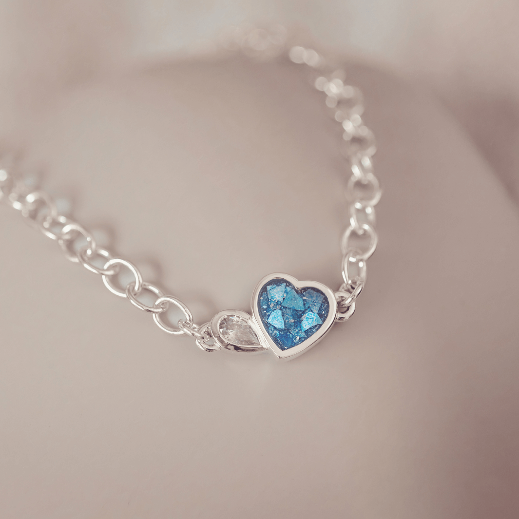 Silver bracelet with a heart-shaped blue gemstone on a soft background