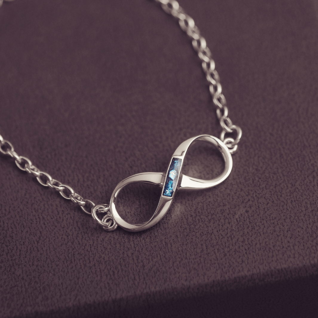 Silver infinity necklace with a blue gemstone on a dark purple background