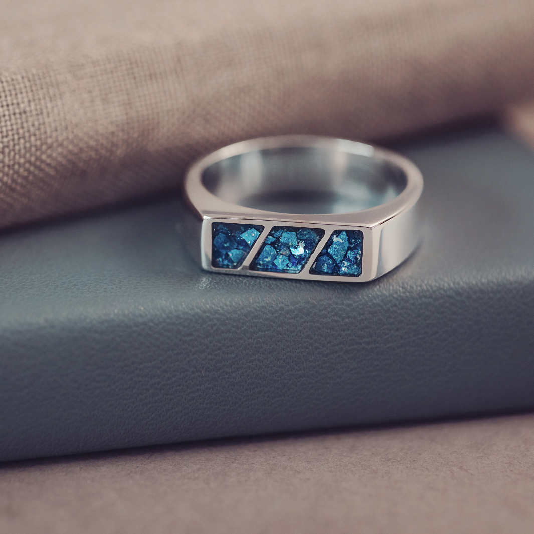 Silver ring with blue gemstones on a textured surface