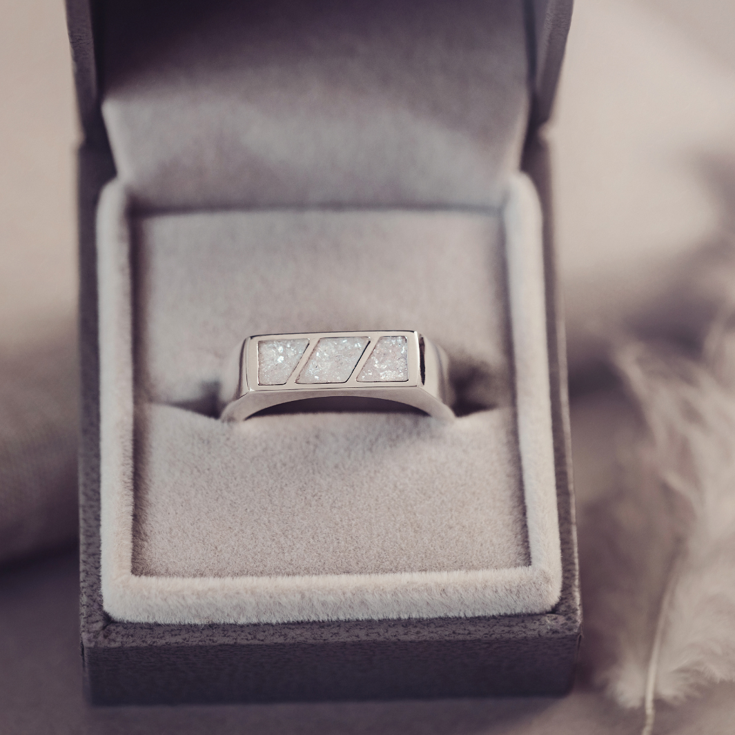 Silver ring with gemstones in a gray jewelry box