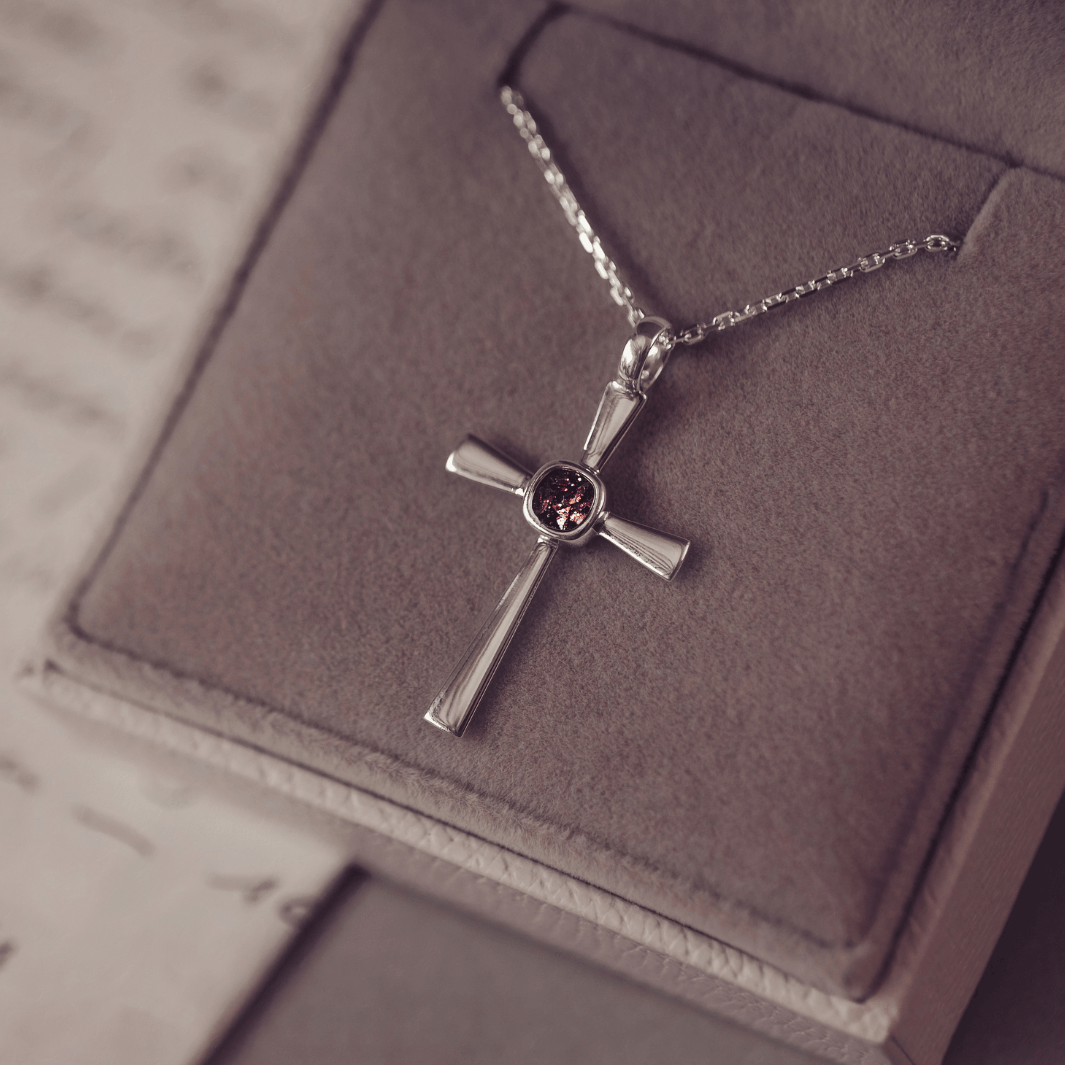 silver cross necklace with a section of resin and brown crystals, holding memorial ashes