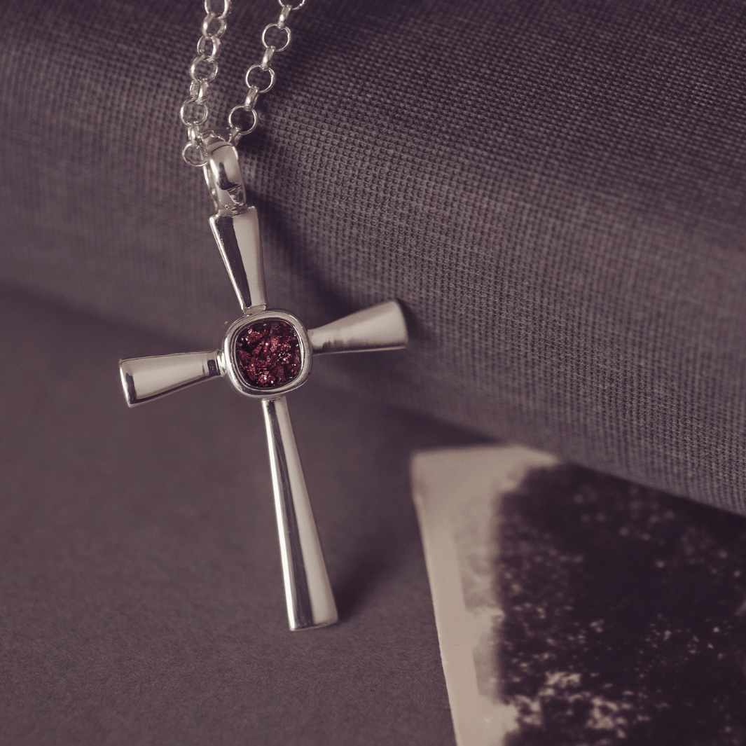 silver cross necklace with a section of resin and brown crystals, holding memorial ashes