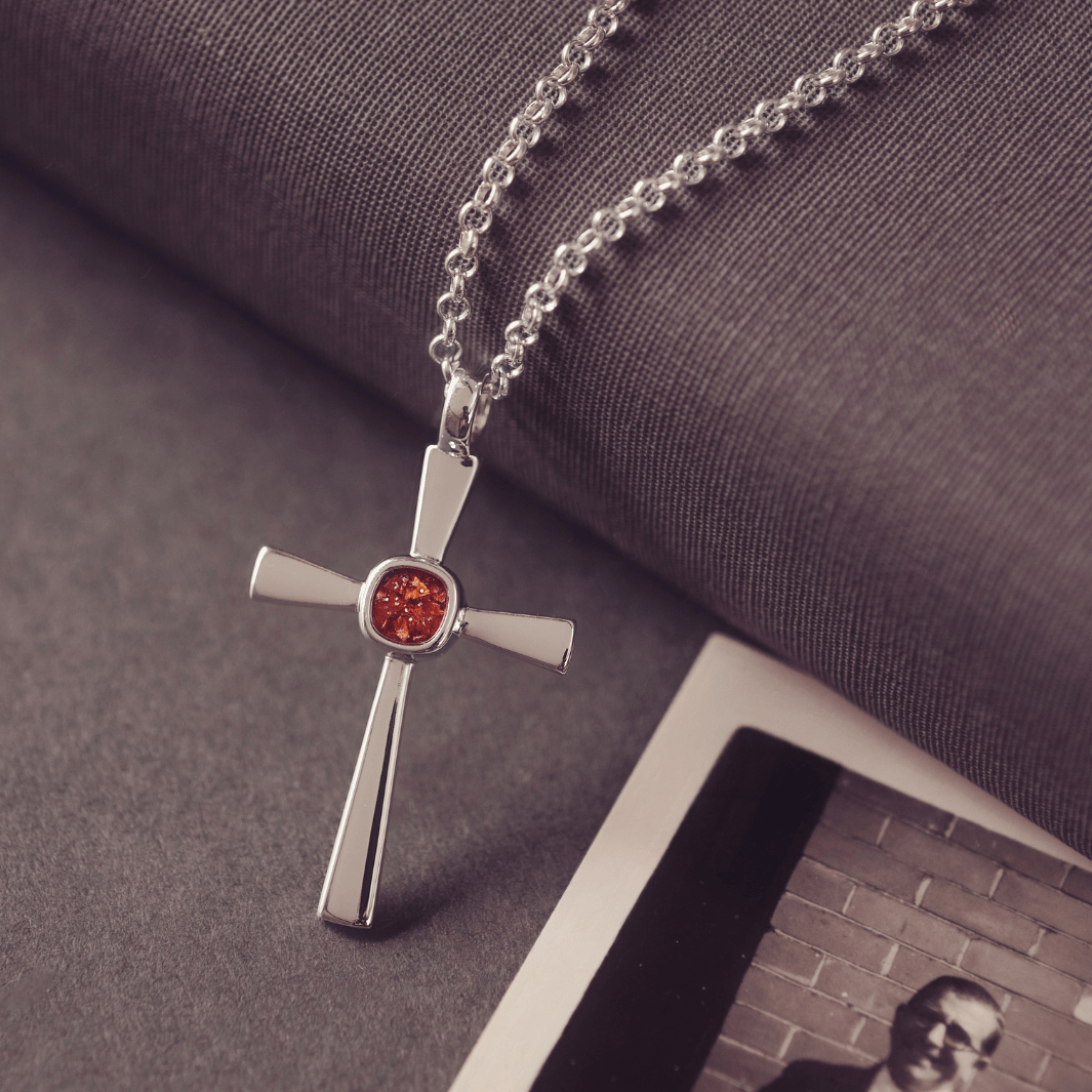 silver cross necklace with a section of resin and orange crystals, holding memorial ashes