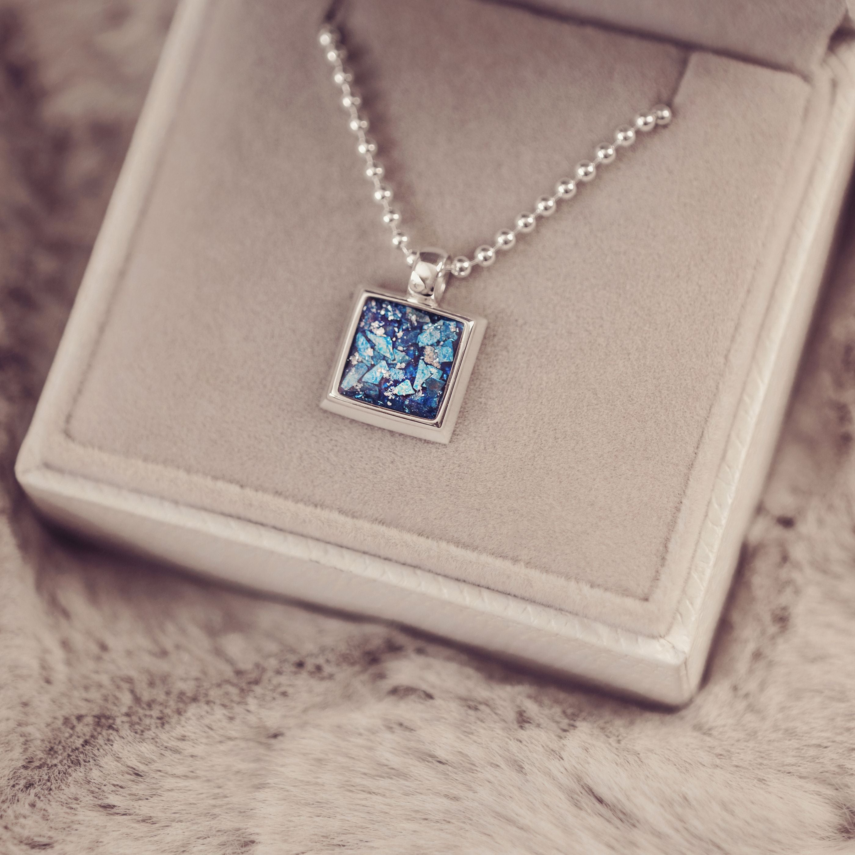 Necklace with a blue pendant on a textured surface