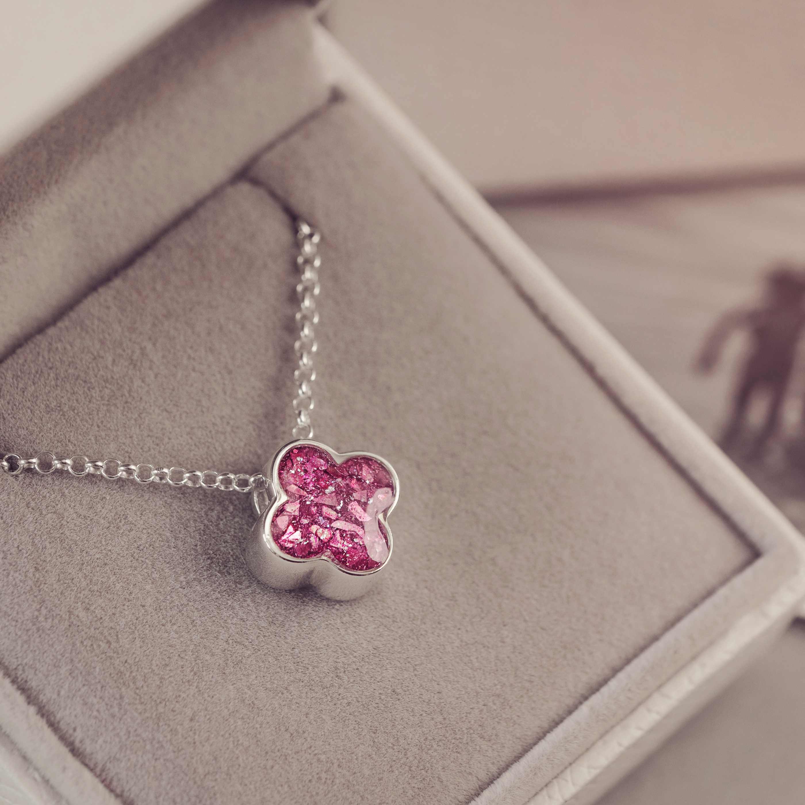 Pink clover-shaped pendant on a silver chain in a jewelry box