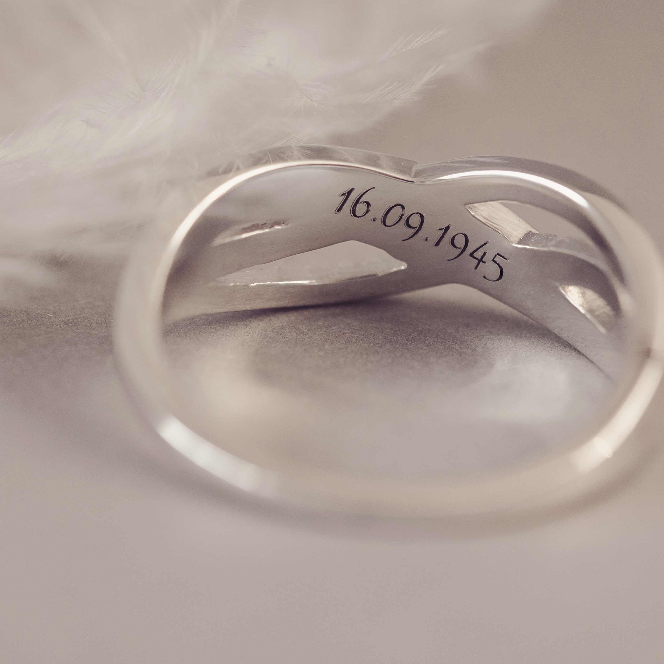 Silver ring with engraved date on a soft fabric background