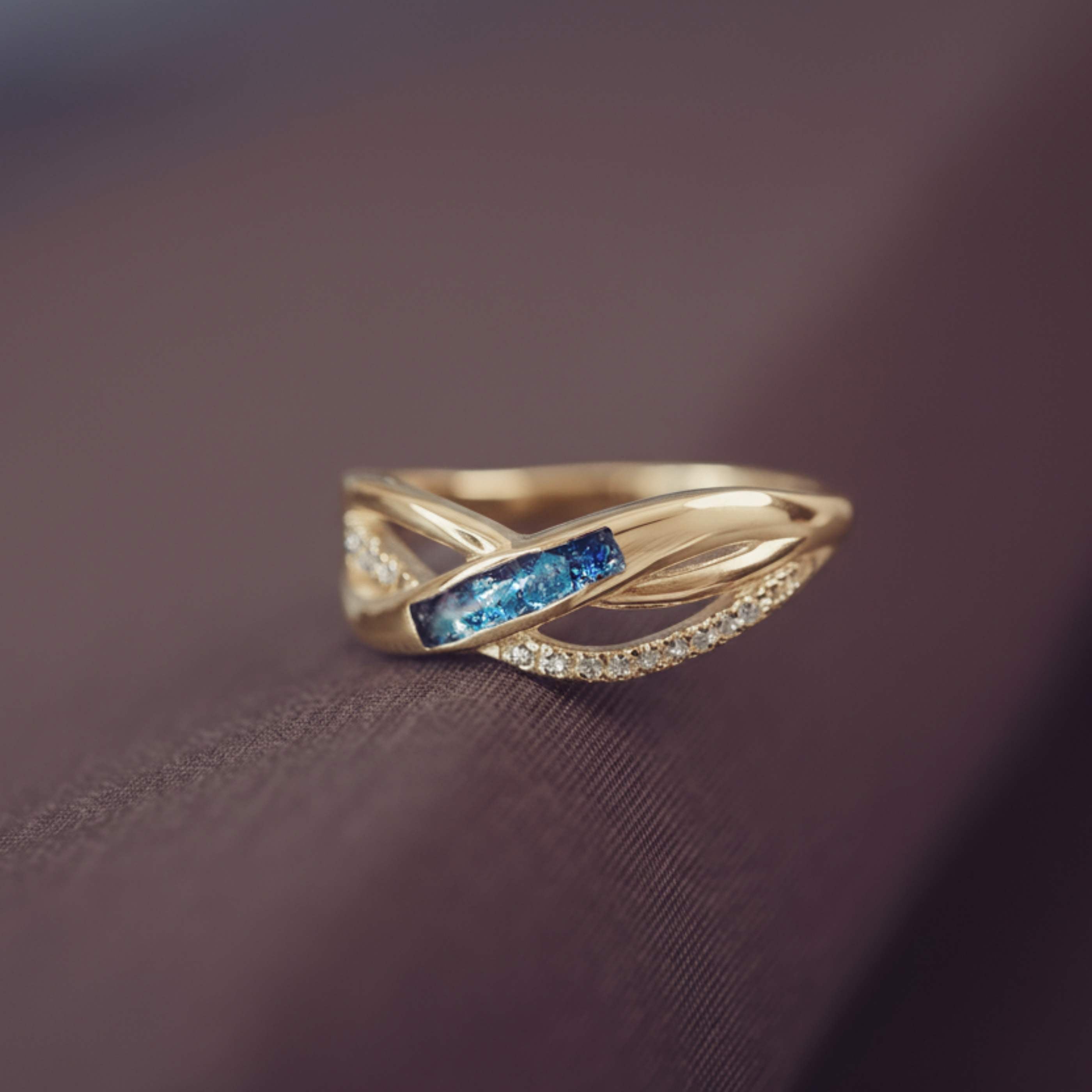 Gold ring with blue gemstone on a dark fabric background