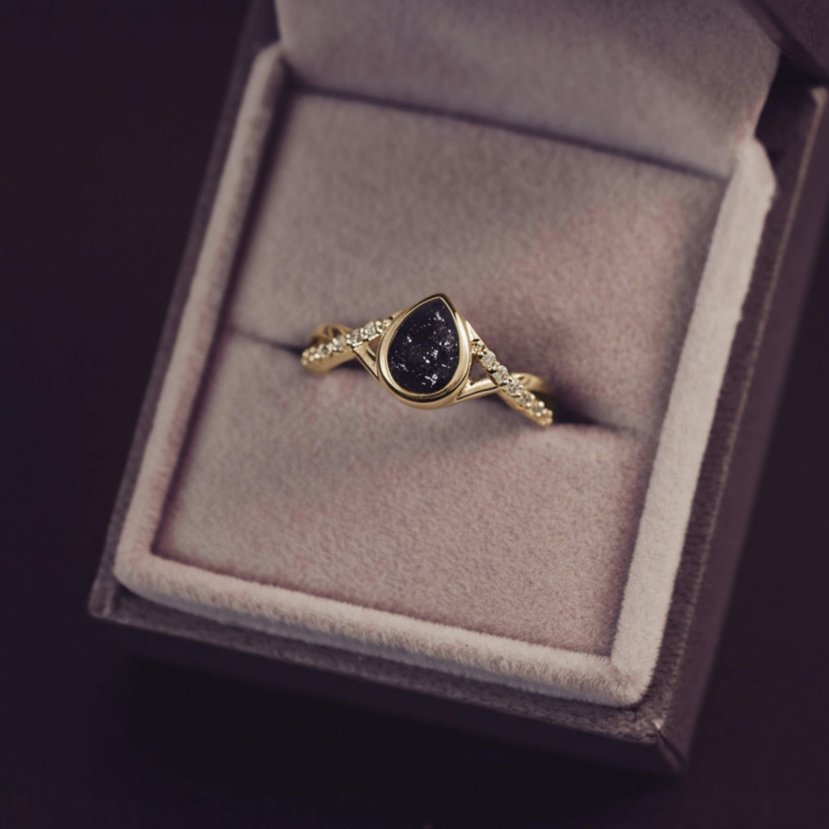 Gold ring with a dark gemstone in a jewelry box