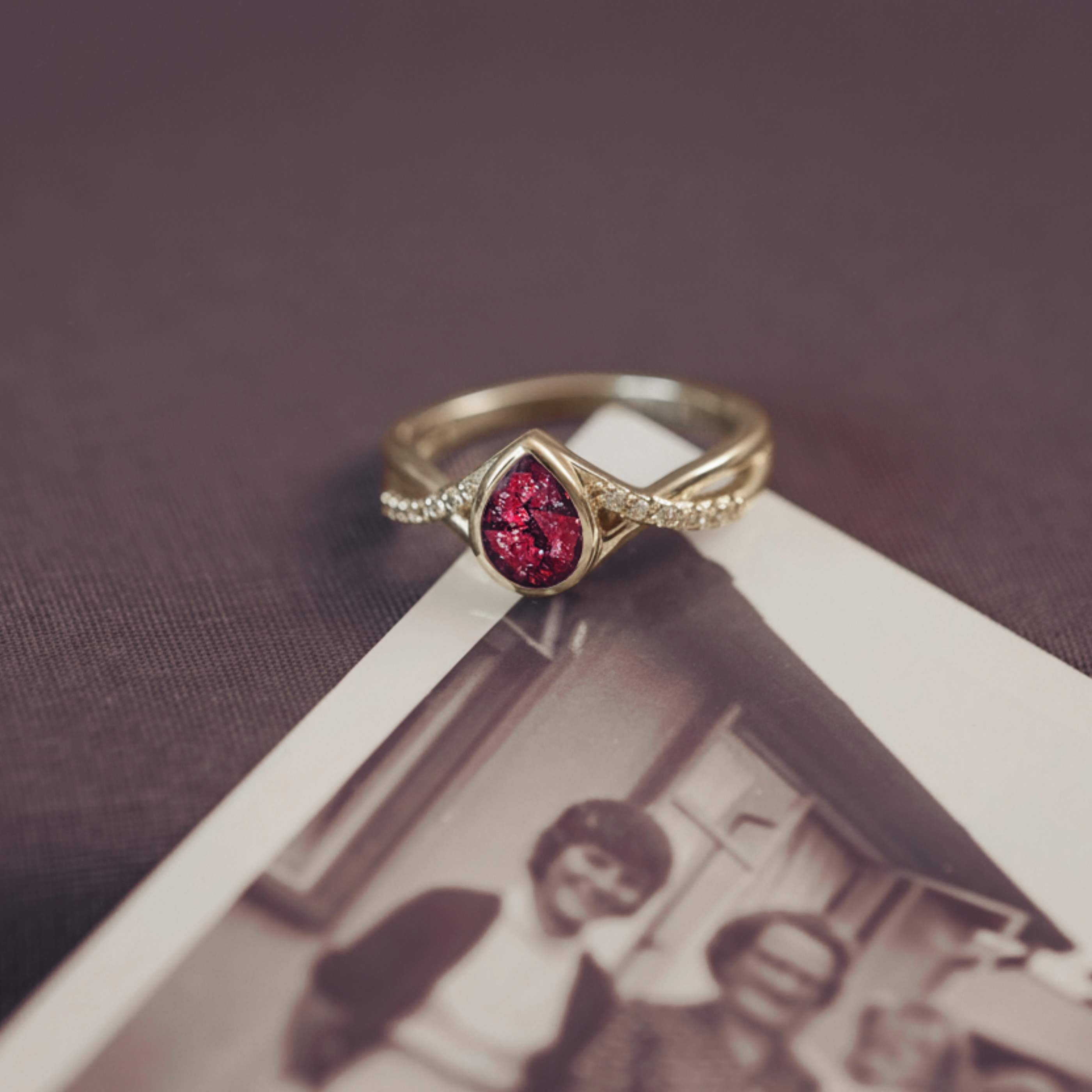 Gold ring with a red gemstone on top of an old photograph